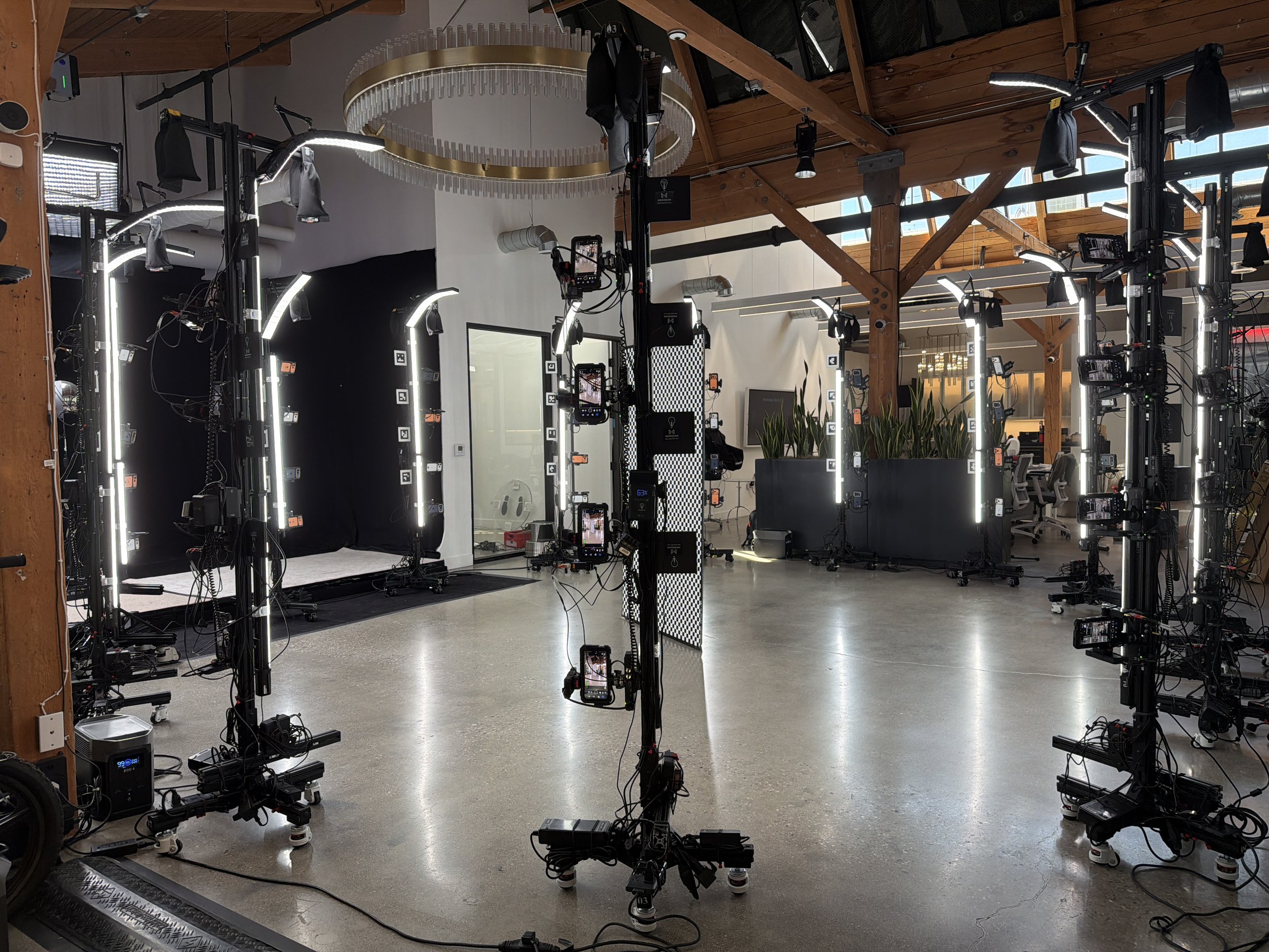 Photo of a professional photography studio setup with multiple camera rigs, lighting equipment, and monitors inside a spacious, wooden-ceilinged room.