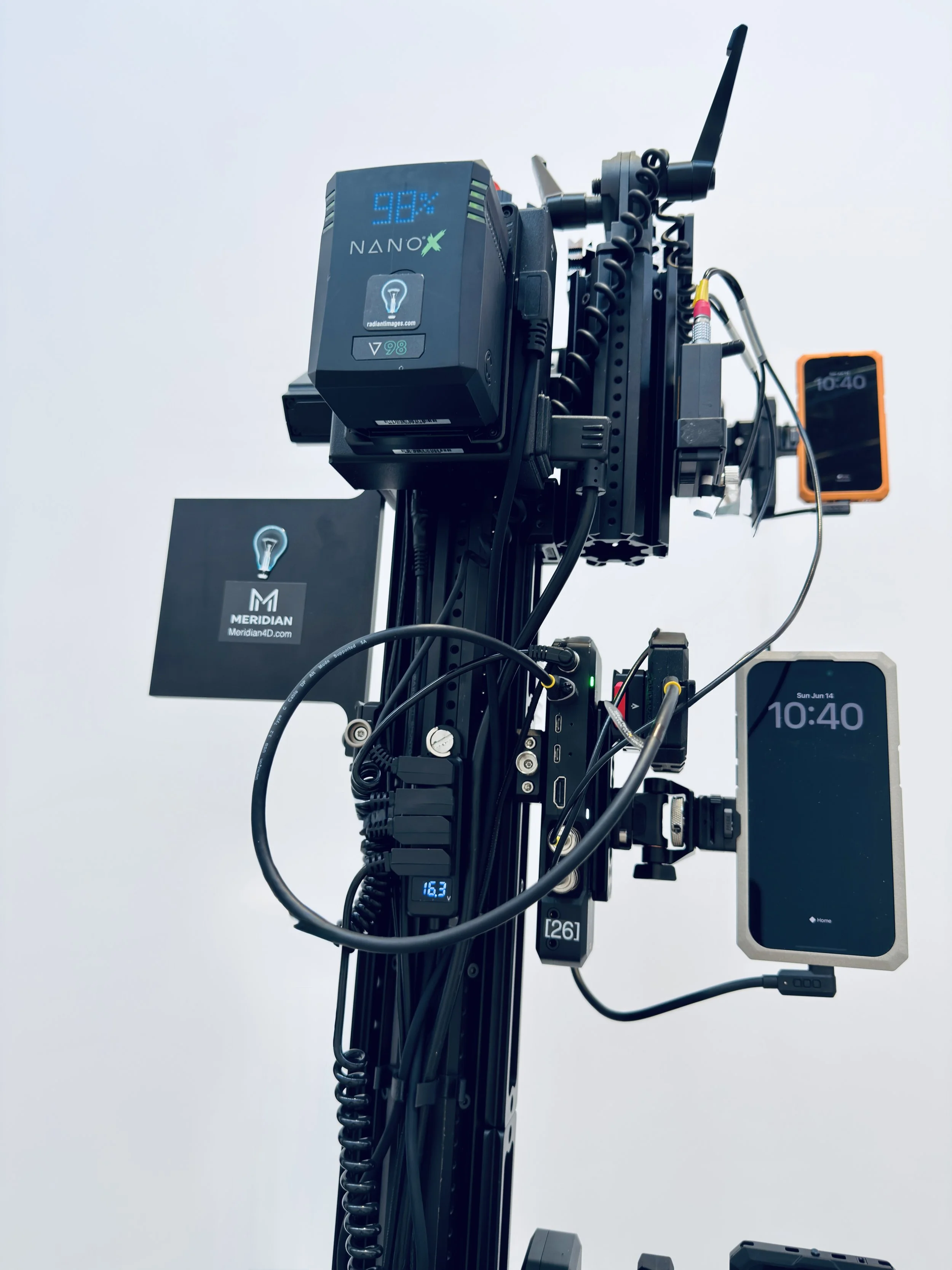 Close-up of a camera rig with electronic devices and wires, including a monitor displaying the time 10:40 and various digital readings.