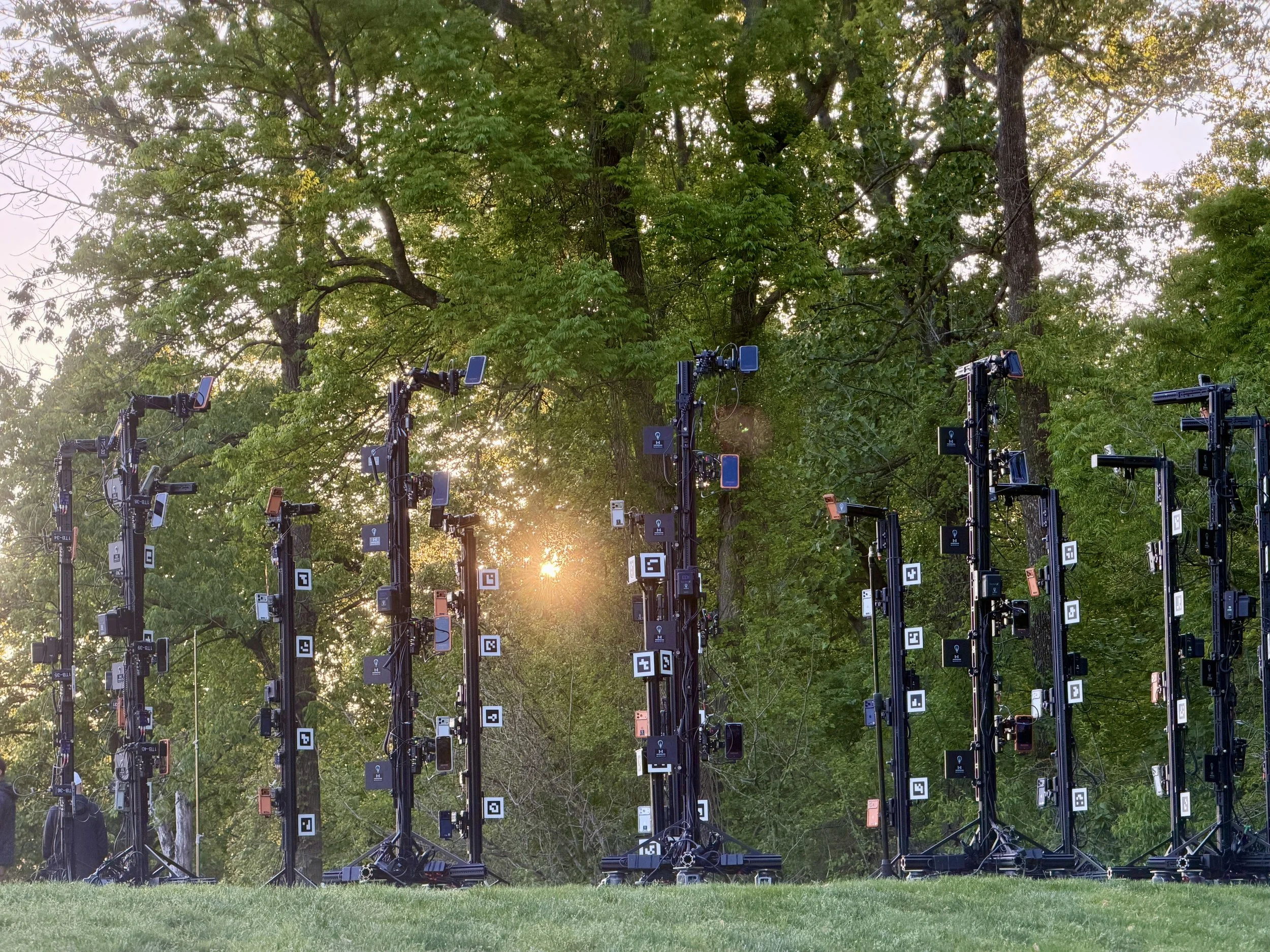 Photo of various smartphone iphones mounted on black stands outdoors on a golf course PGA Meridian 4D portable volumetric gaussian splat system