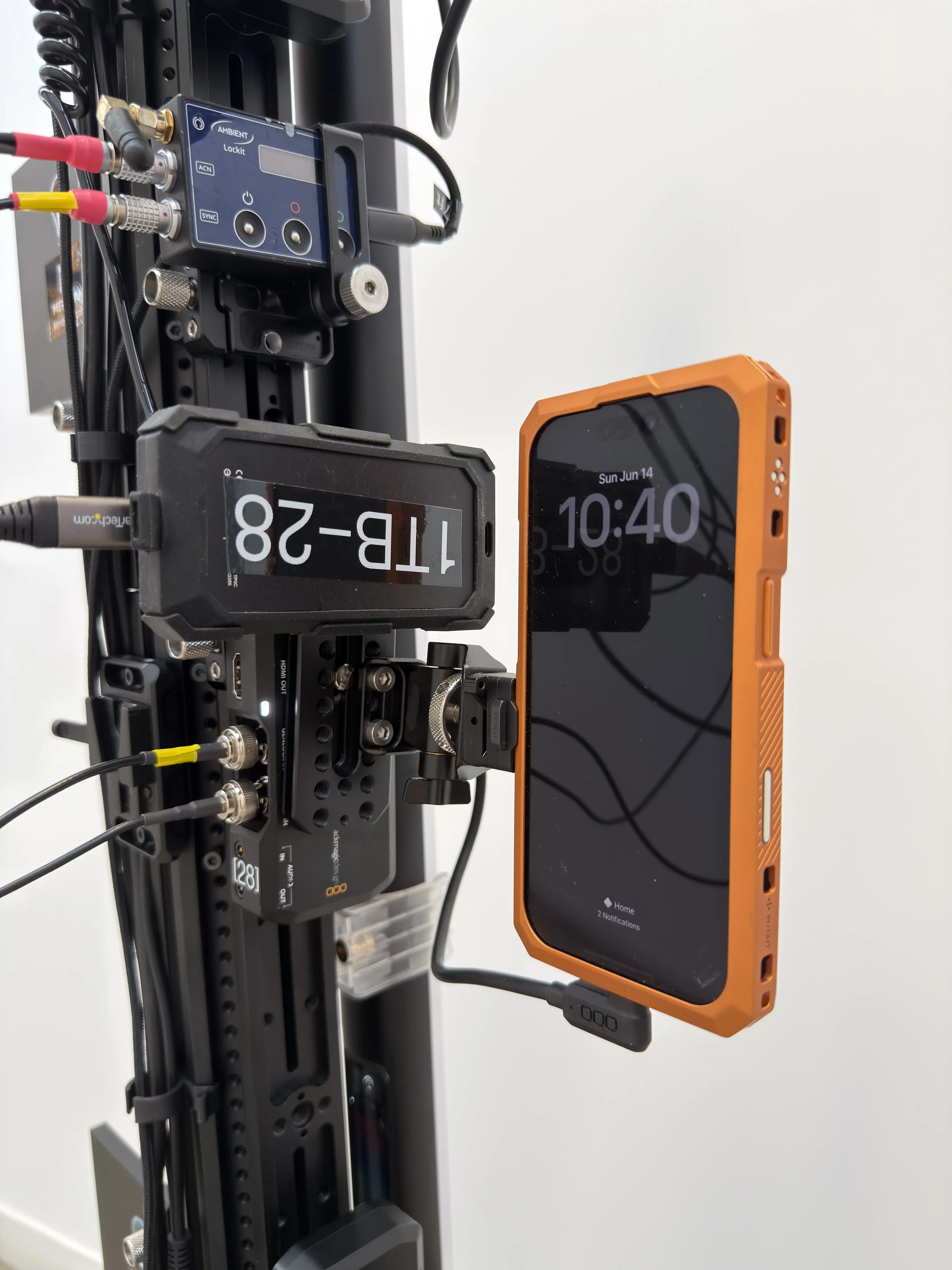 A close-up of a scientific or industrial setup with electronic equipment including a control panel with wires, connectors, and a smartphone attached to the setup. Meridian 4D portable volumetric gaussian splat system