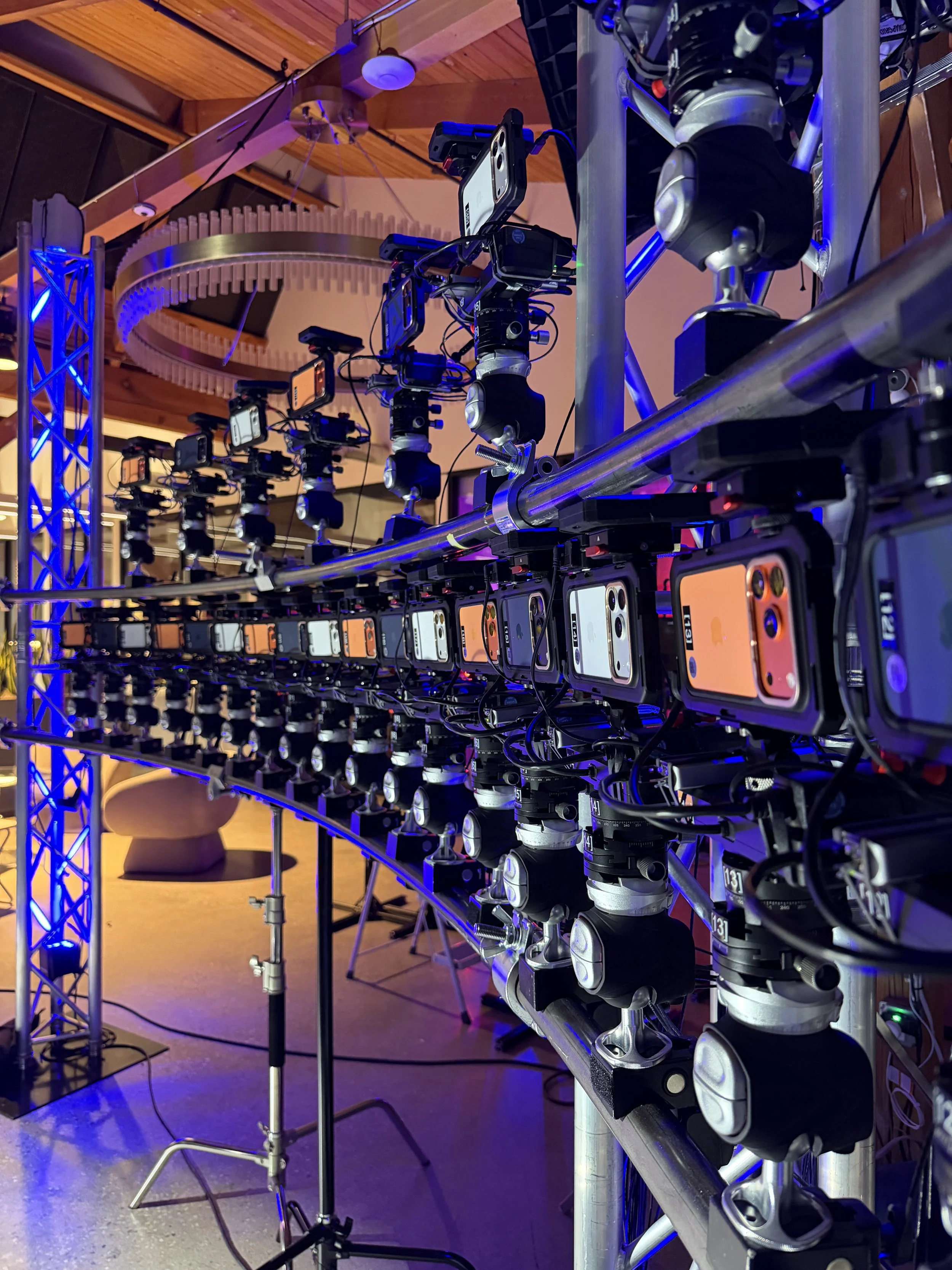 Multiple smartphones mounted on robotic arms, set up on a metal framework Meridian 4D portable volumetric gaussian splat system iPhone 