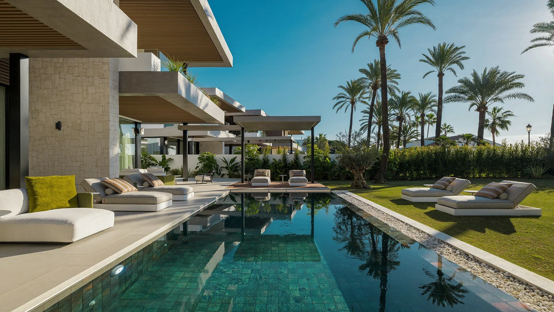 Casa moderna de varios pisos con balcones, ventanas grandes y un patio con área de descanso, césped y árboles