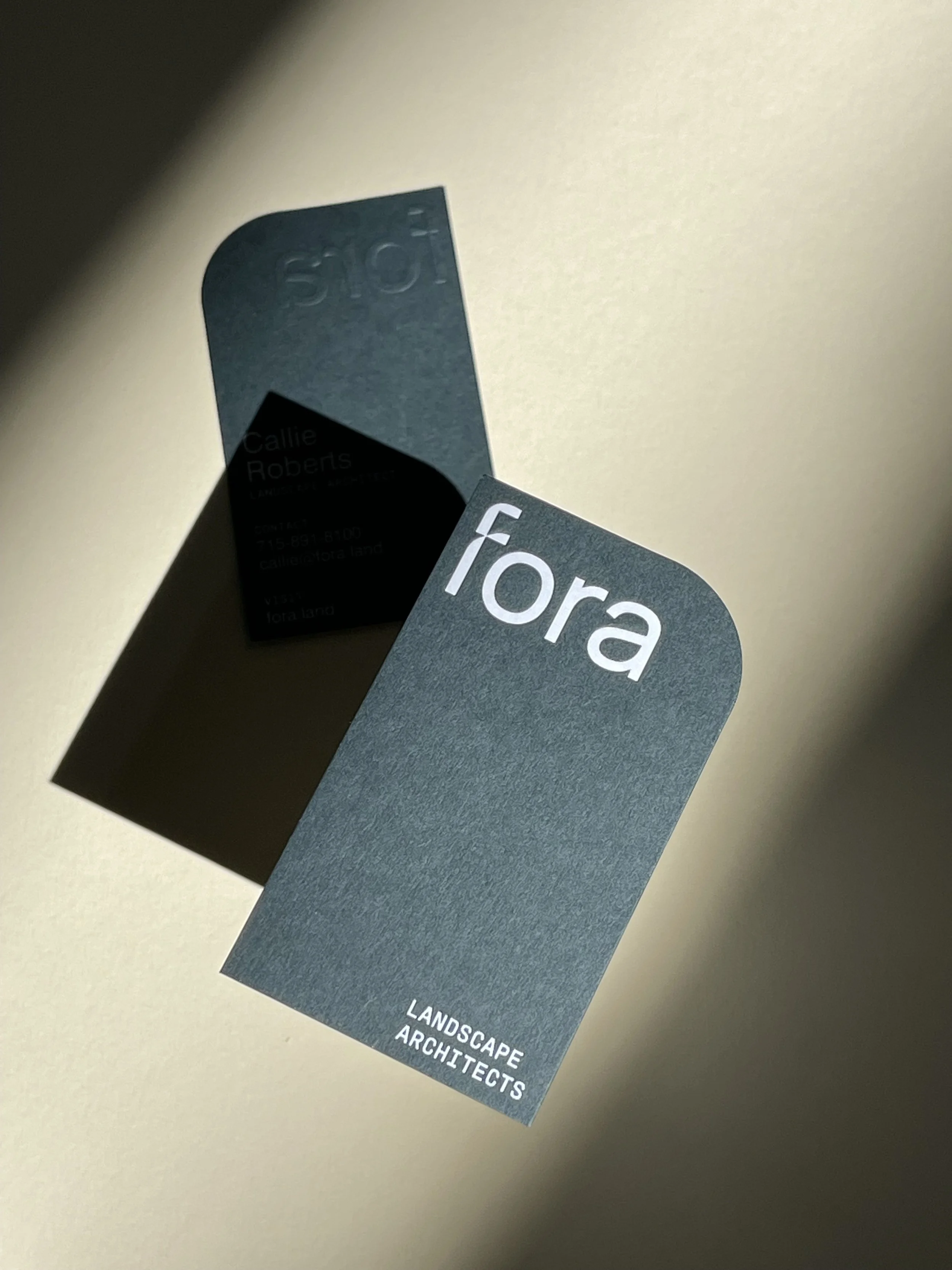 Business card for 'fora Landscape Architects' with a shadow cast on a light-colored surface.