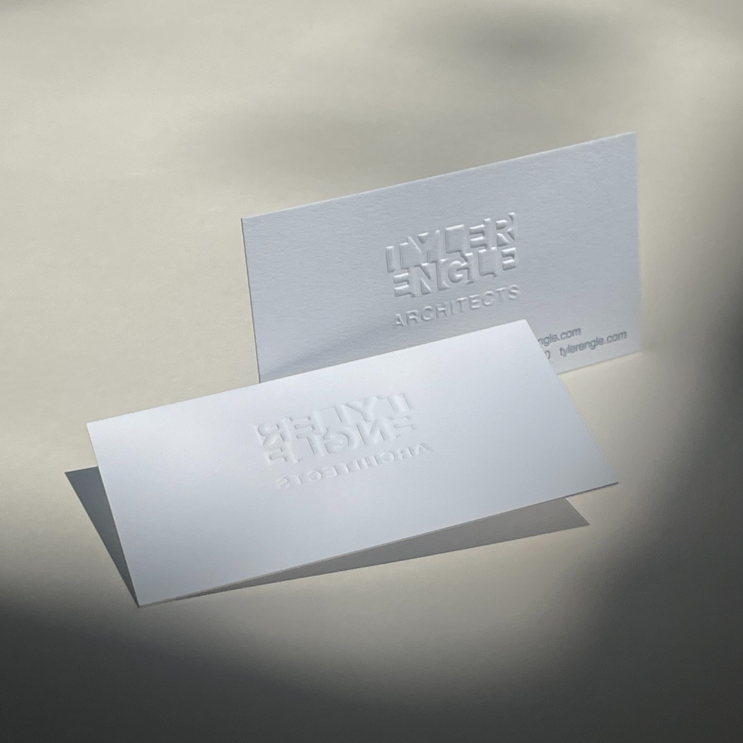 Two white business cards with embossed text for Lyser Angle Architects, one standing upright and one lying down on a plain surface.