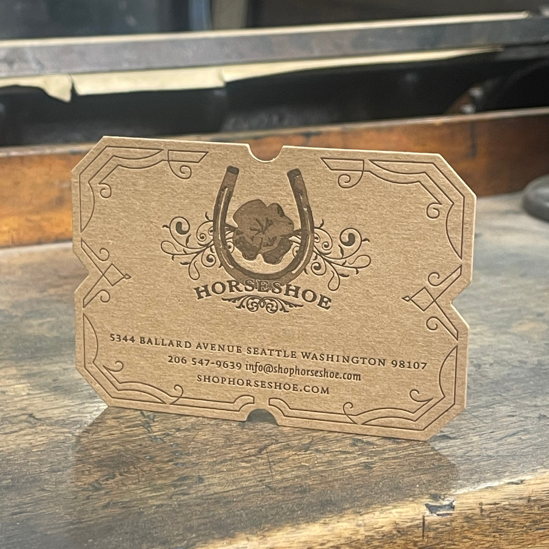 A wooden business card for Horseshoe, featuring a horseshoe and horse design, with contact information including address in Seattle, Washington, phone number, email, and website.