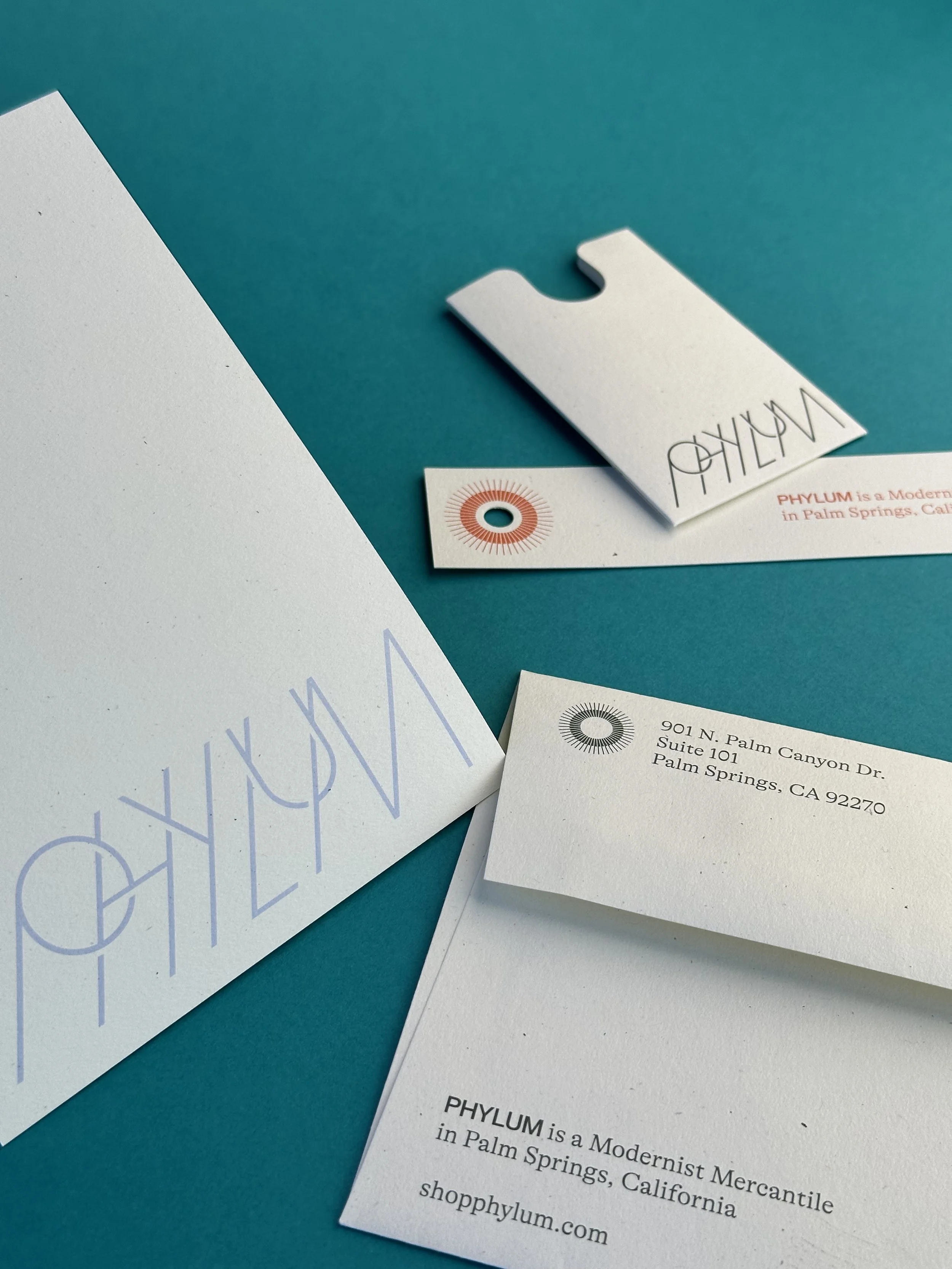 Business stationery including an envelope, a business card, and a small tag with a modern logo and contact information for PHYLUM, a company based in Palm Springs, California.