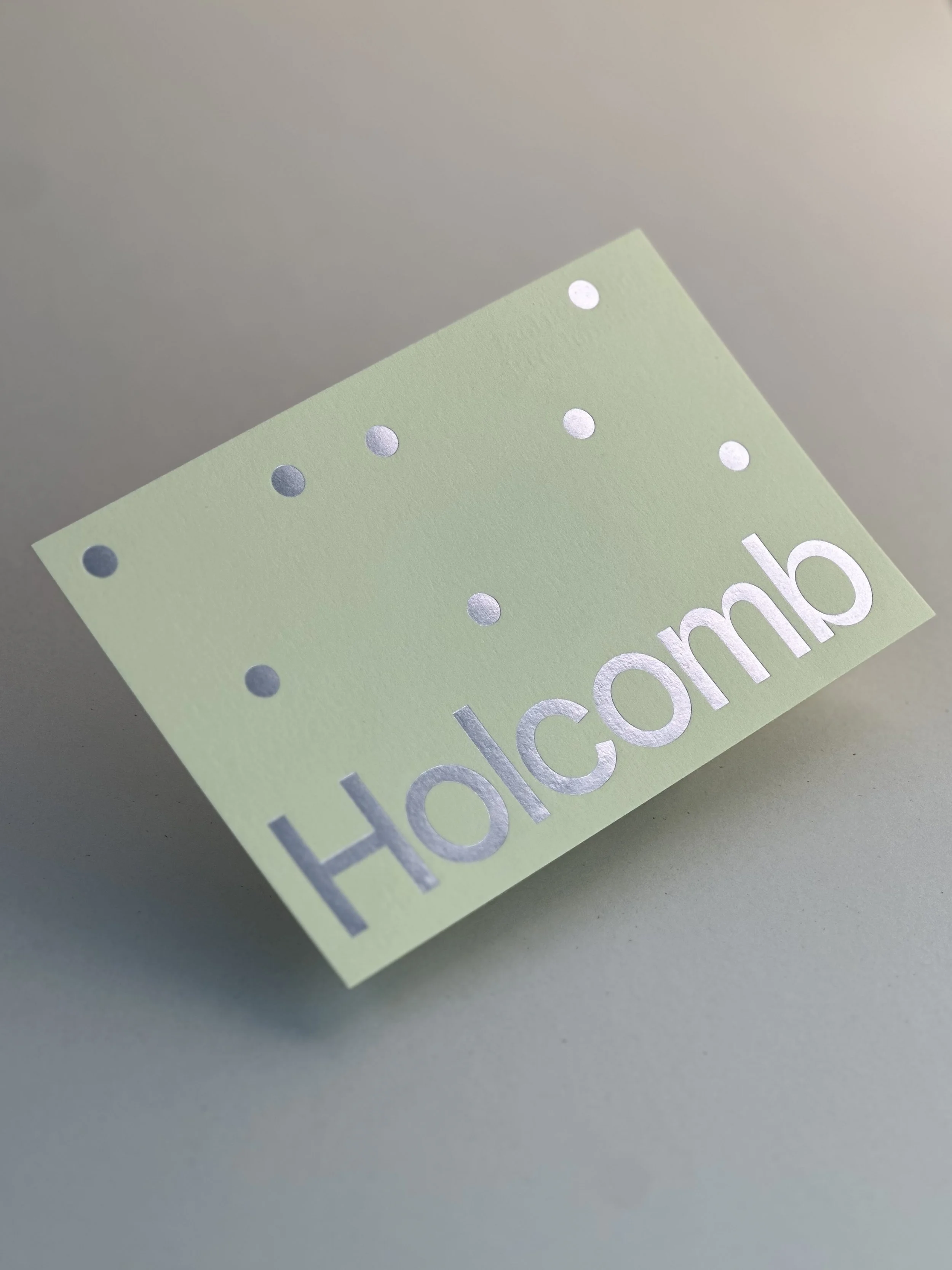 A light green paper with shiny silver dots and the words 'Holidomb' printed in silver.