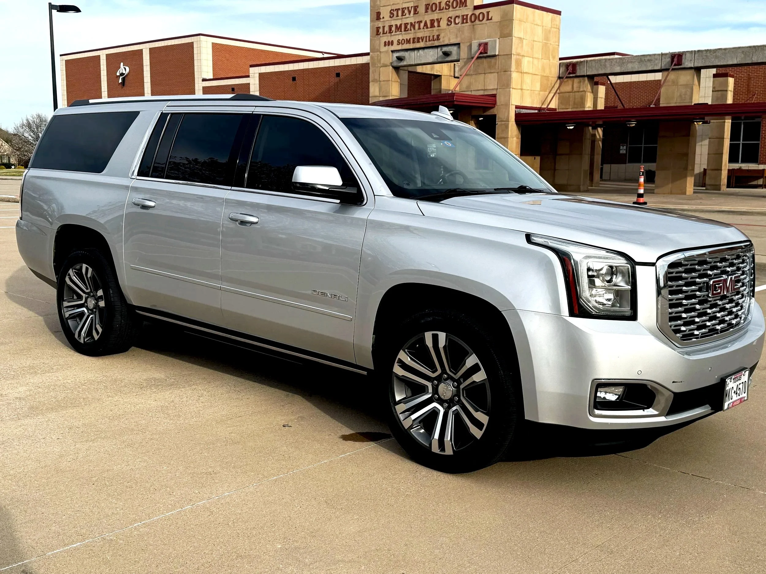 Silver GMC Denali SUV parked in front of R. Steve Folsom Elementary School building.