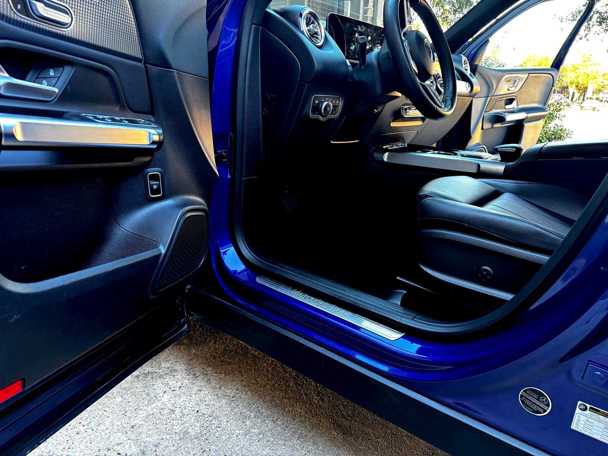 Interior of a blue Mercedes-Benz vehicle showing the driver's seat, steering wheel, and dashboard.