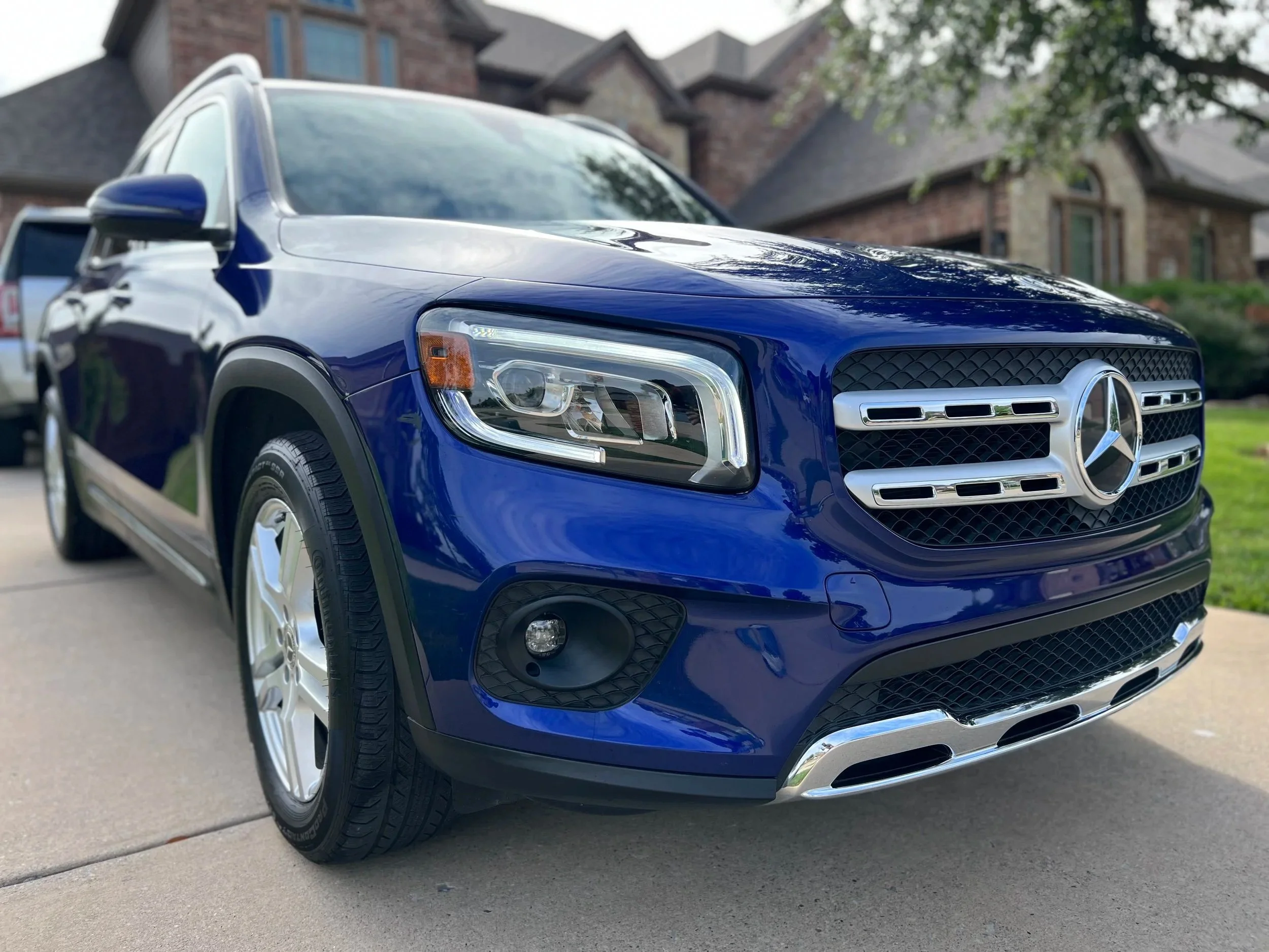 Front view of a blue Mercedes-Benz SUV parked on a driveway in front of a house.