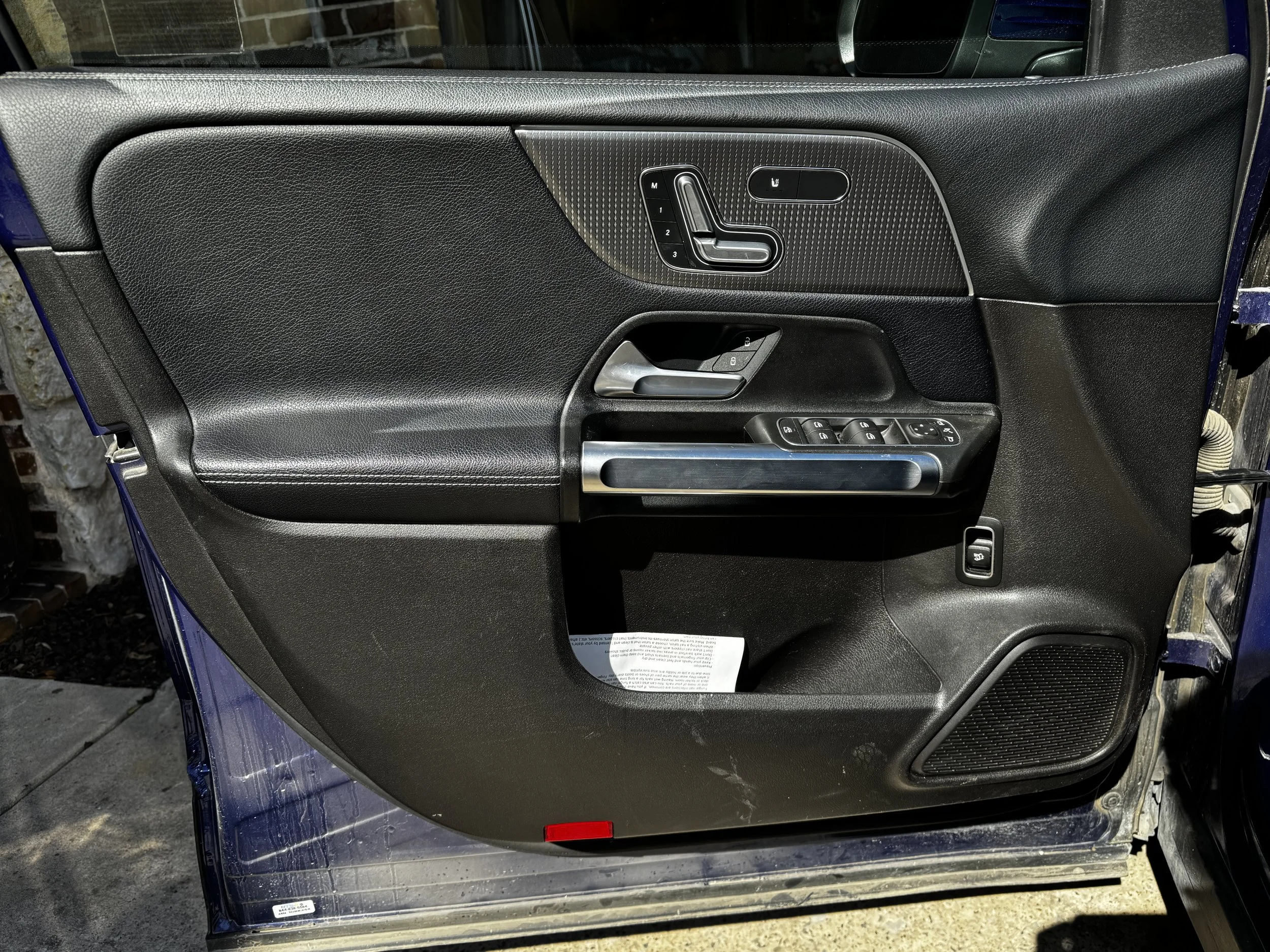 Close-up of a car door's interior panel with controls for seat adjustment, window switches, and a door handle.
