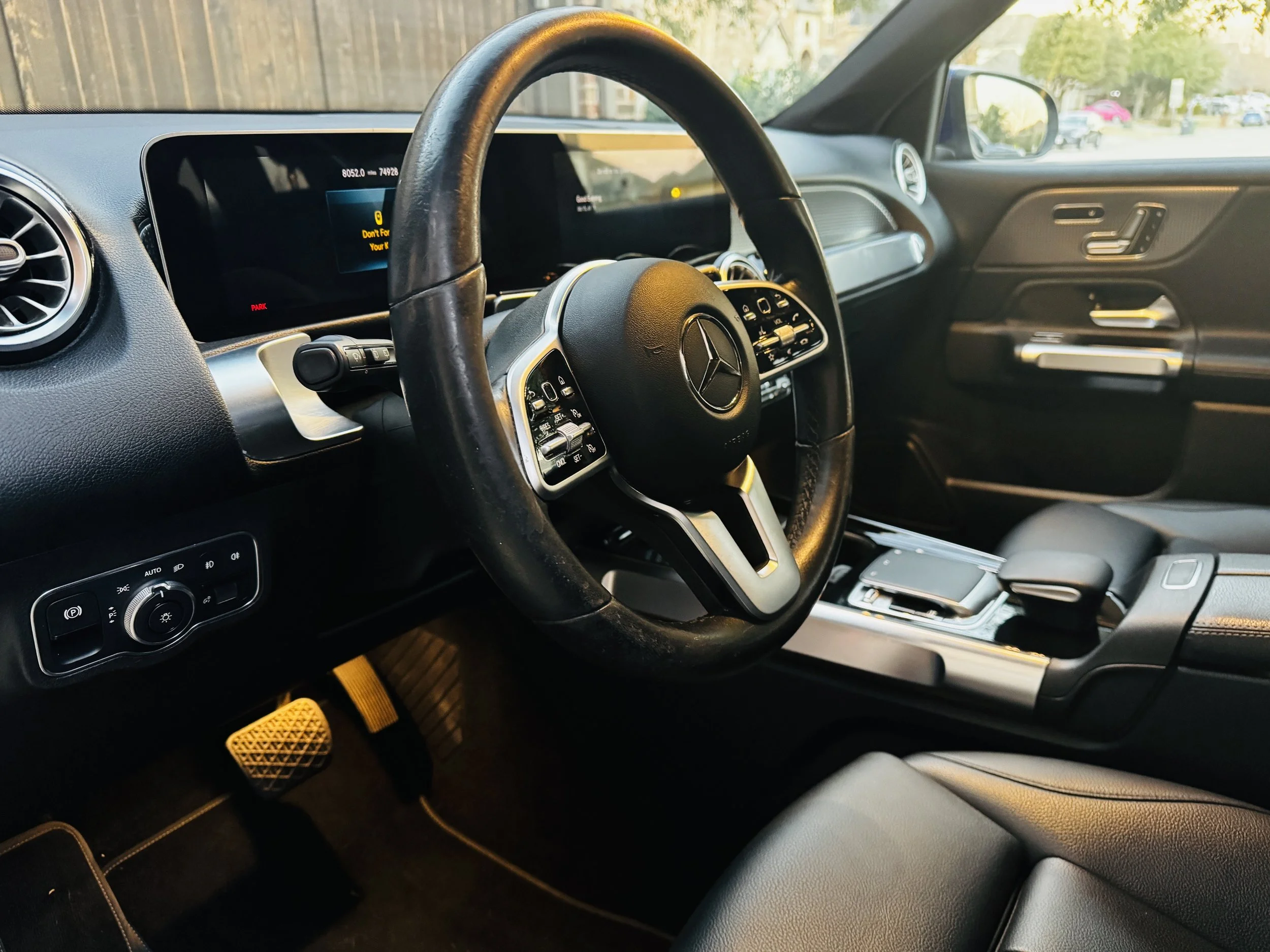 Interior of a Mercedes-Benz vehicle, focusing on the steering wheel, dashboard, and driver-side door panel.
