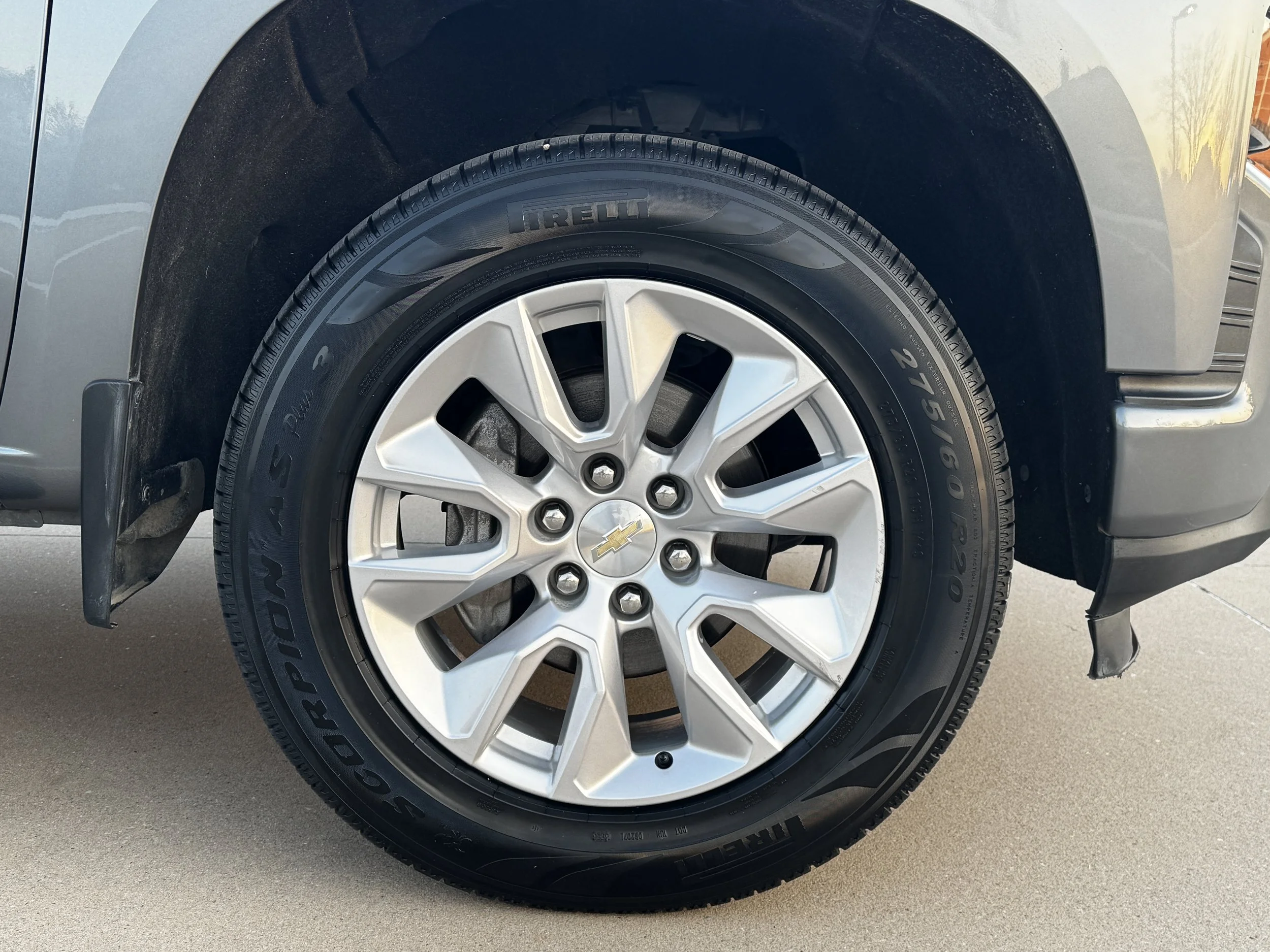 Close-up of a vehicle's tire and wheel, featuring an alloy rim with a Chevrolet logo in the center, Pirelli tire tread, and part of the vehicle's gray body and black wheel arch.
