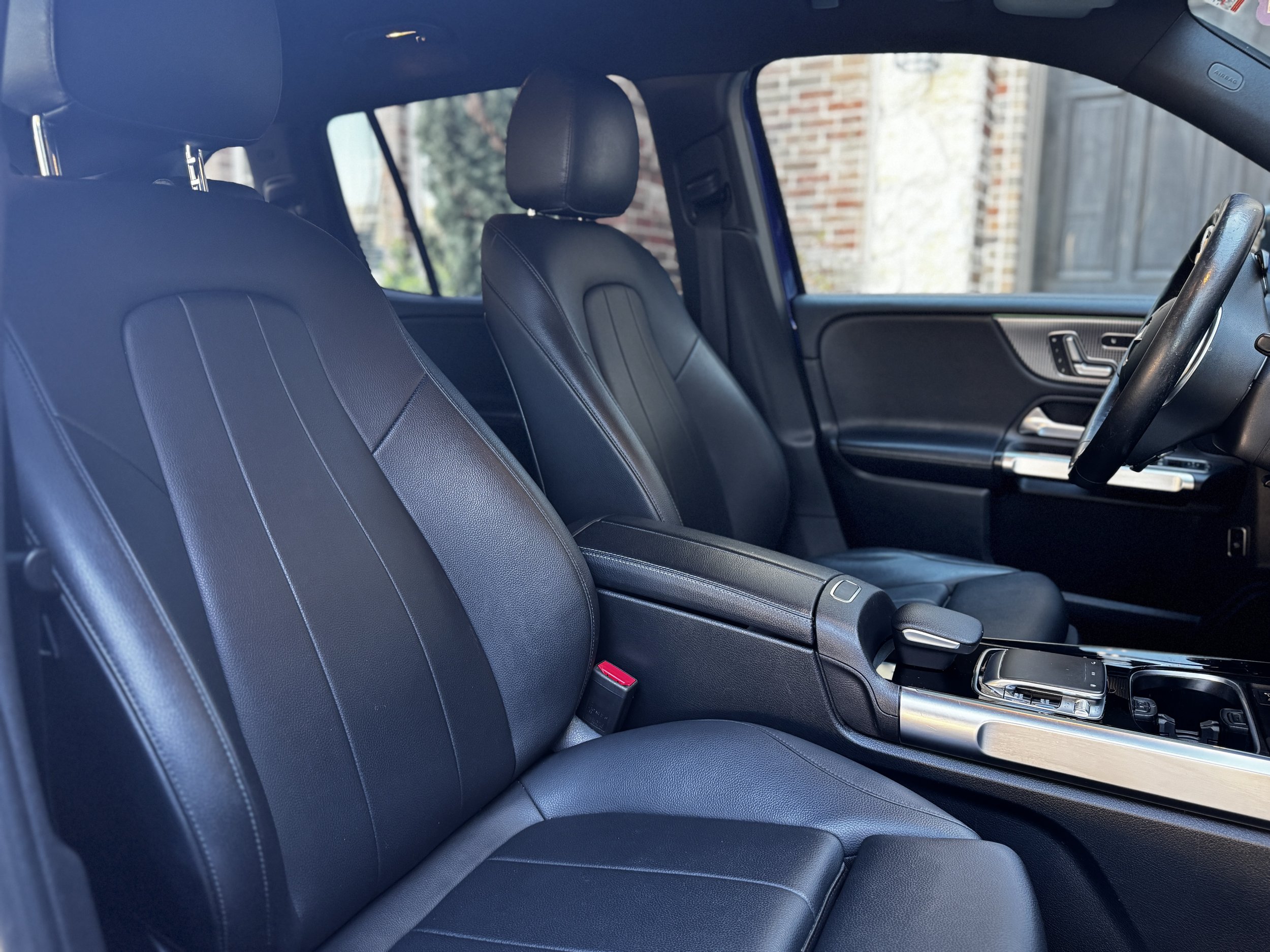 Interior of a modern vehicle showing black leather seats, dashboard, and center console with car keys.