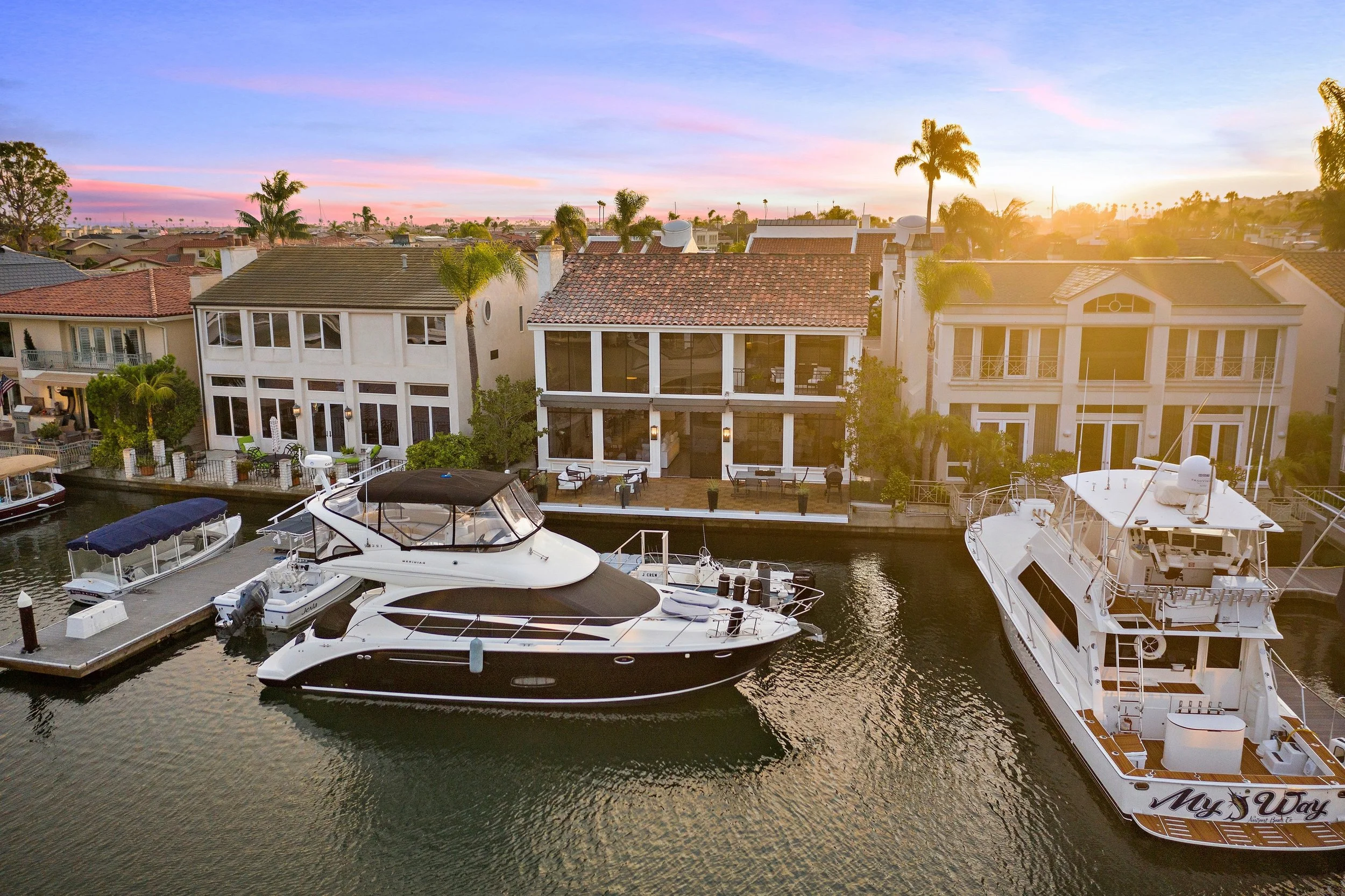 Luxury waterfront homes with private docks and yachts at sunset.