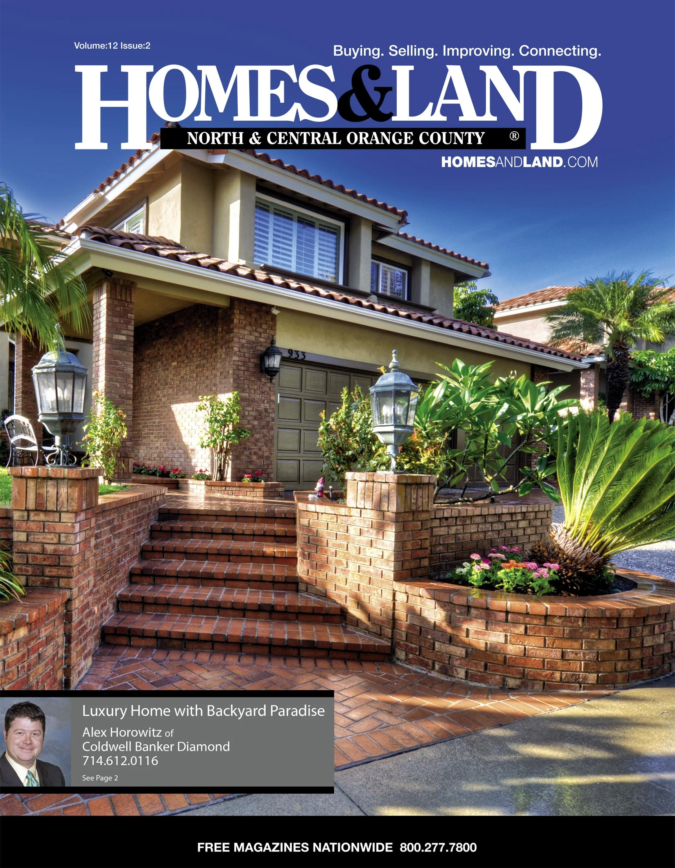 Cover of Homes & Land magazine featuring a two-story house with brick and stucco exterior, a tiled roof, brick stairs, and lush landscaping with palm trees and flowering plants.