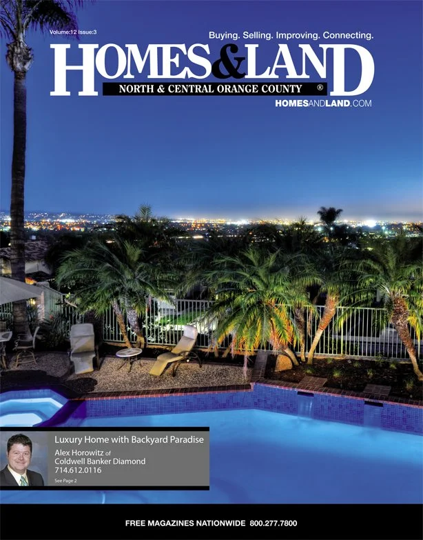 Cover of Homes & Land magazine featuring a nighttime view of a backyard with a swimming pool, palm trees, and city lights in the distance.
