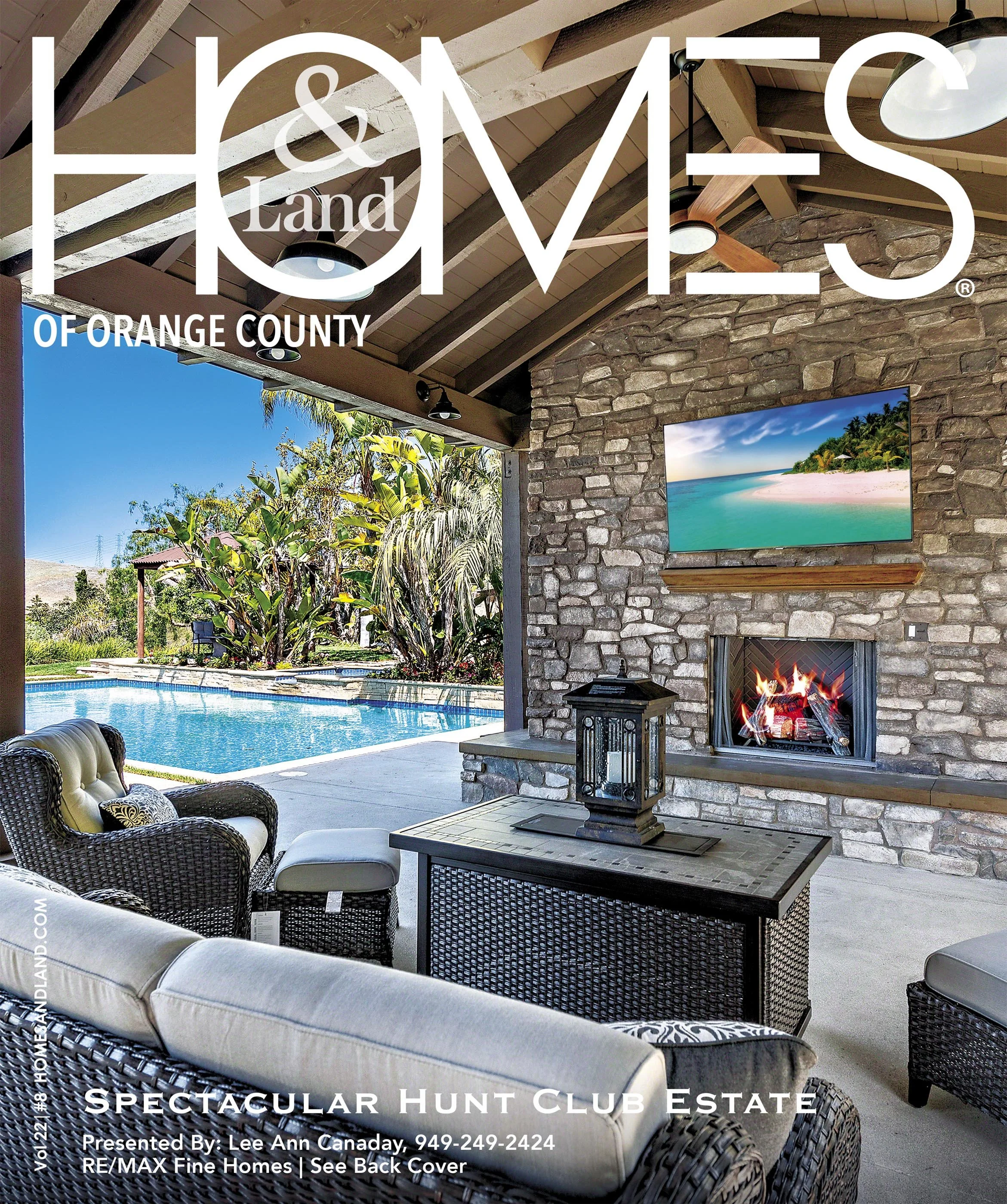 Covered outdoor patio with a stone fireplace, a wall-mounted TV, and seating area overlooking a swimming pool and tropical plants.