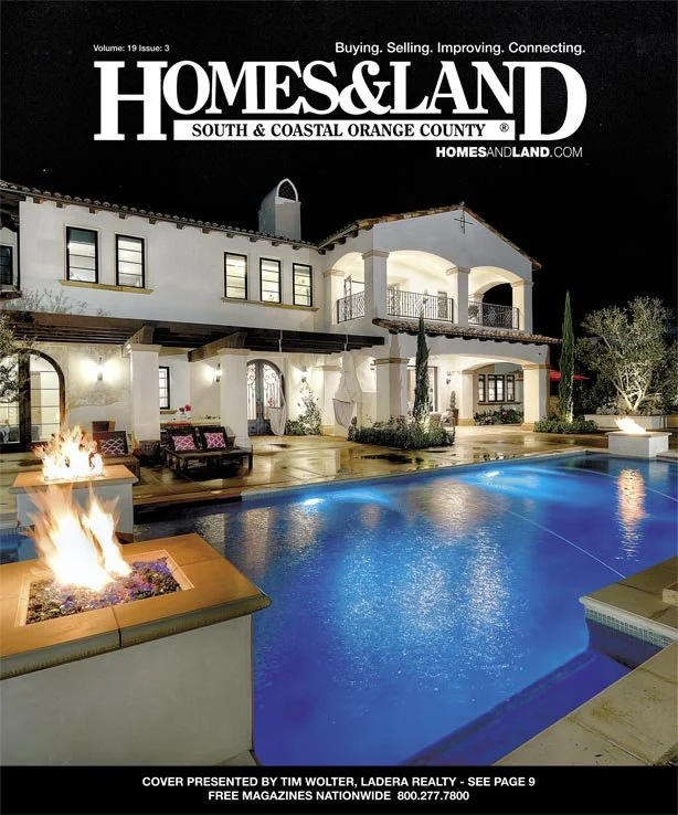 Night view of a luxurious house with a lit swimming pool, outdoor fire pit, and patio furniture, featured on the cover of Homes & Land magazine.