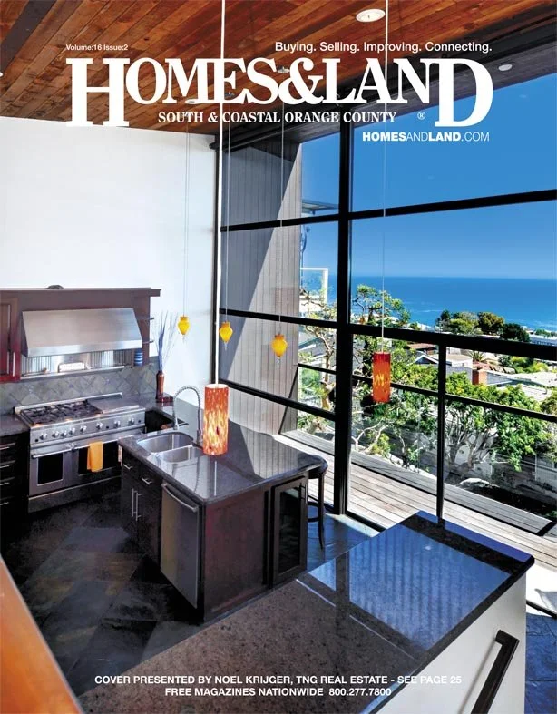 Cover of Homes & Land magazine featuring a modern kitchen with a view of the ocean through large windows.