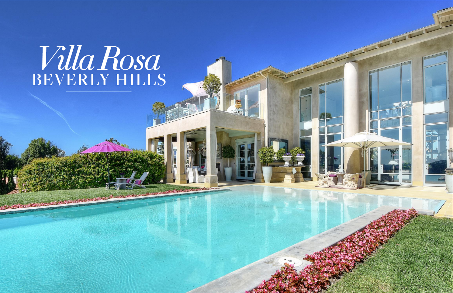 Luxury modern house with large swimming pool, pink flowers along the pool edge, white outdoor furniture with umbrellas, and 