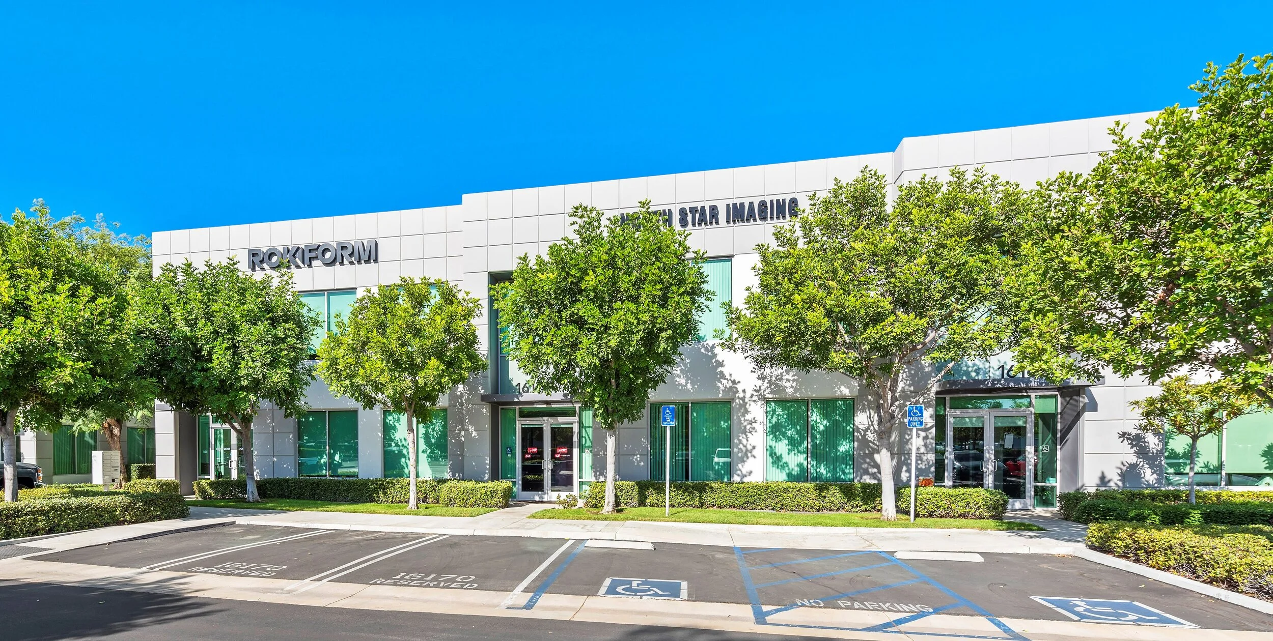 Modern commercial building with green trees and a parking lot, labeled 'ROKFORM' and 'Star Imaging' in a bright, sunny setting.