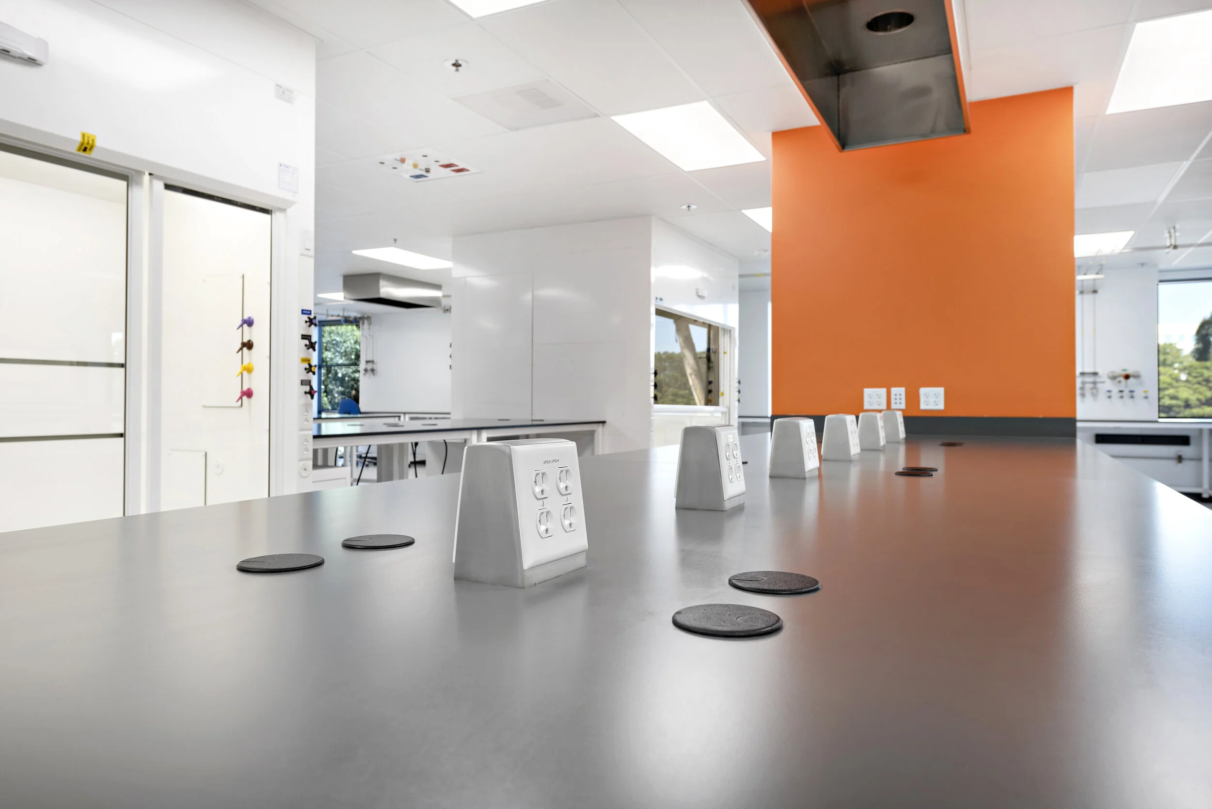 Modern conference room with a long table, power outlets, and orange accent wall.
