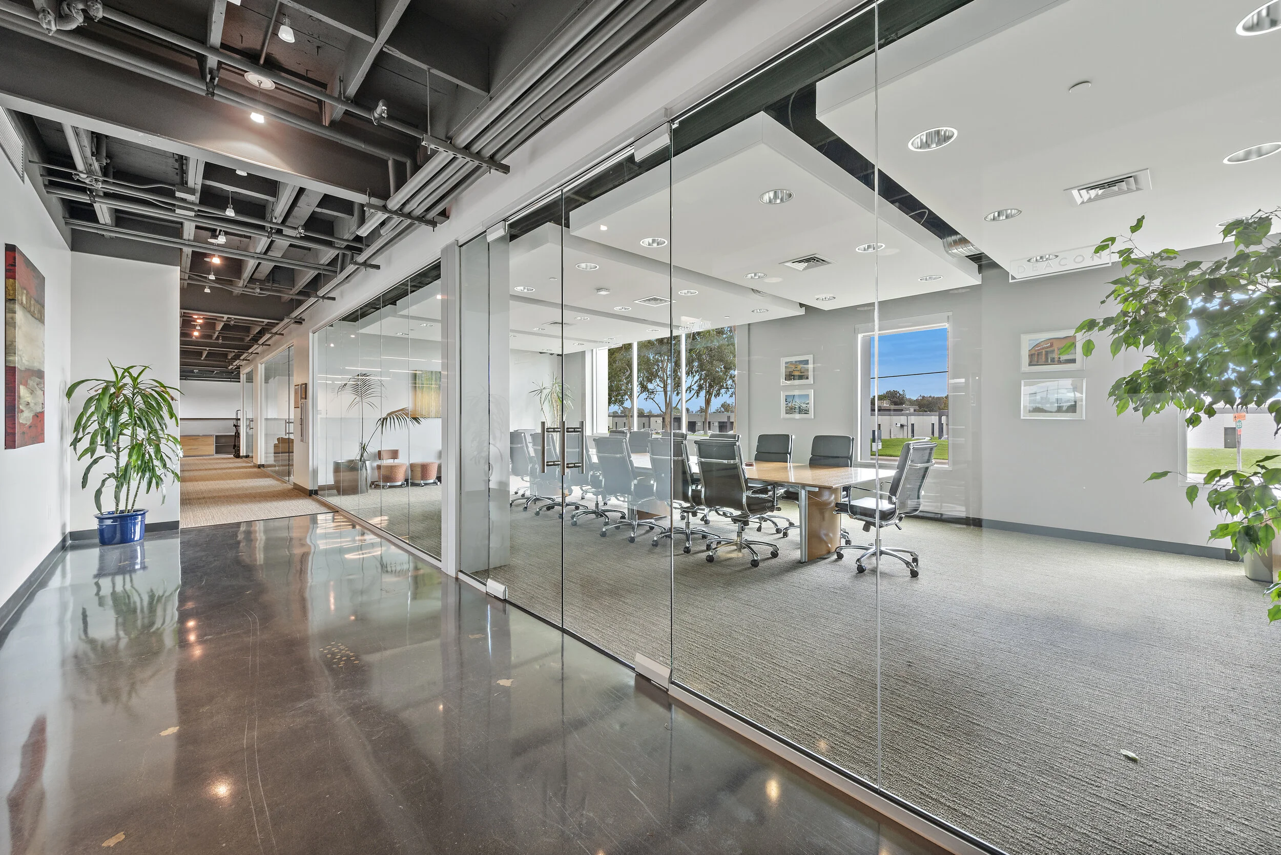 Modern office conference room with large table and chairs, glass walls, and outdoor view
