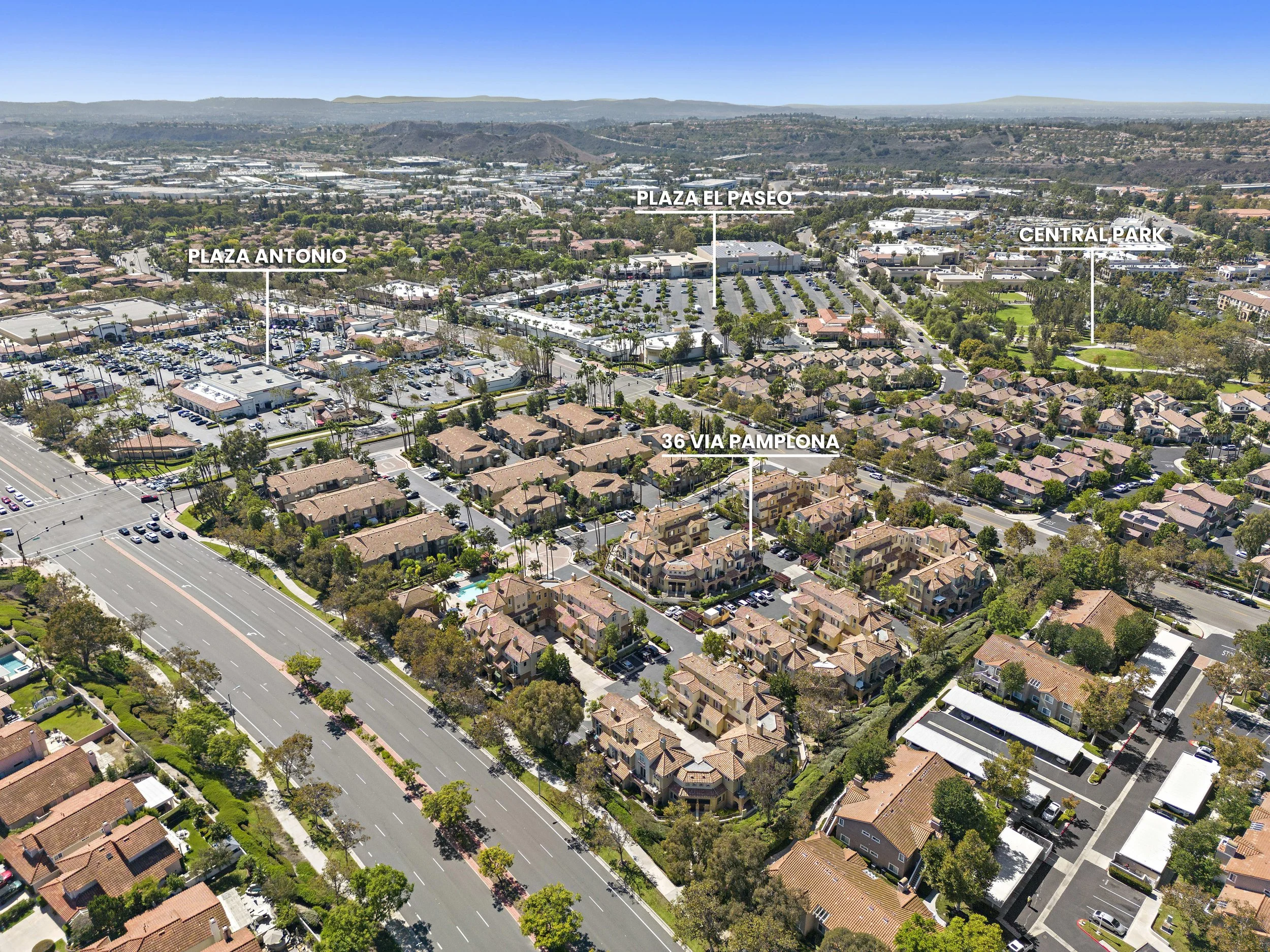 Aerial view of a residential neighborhood with labeled locations including Plaza Antonio, Plaza El Paseo, Central Park, and 36 Via Pamplona, showing streets, houses, parking lots, and green spaces under a clear blue sky.