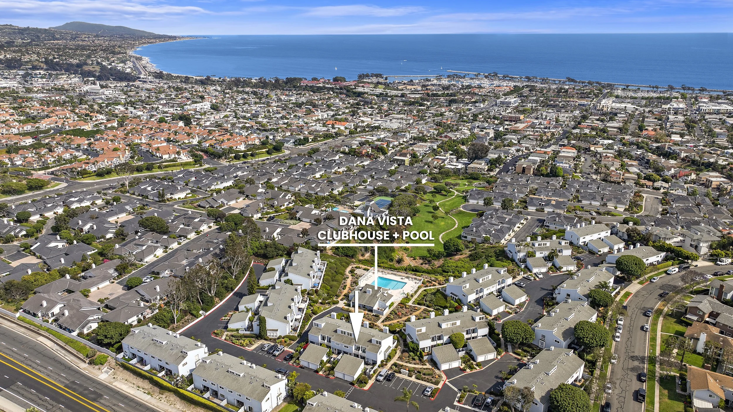 Aerial view of a residential neighborhood with a clubhouse and pool marked as Dana Vista, overlooking the ocean and coastline in the background.