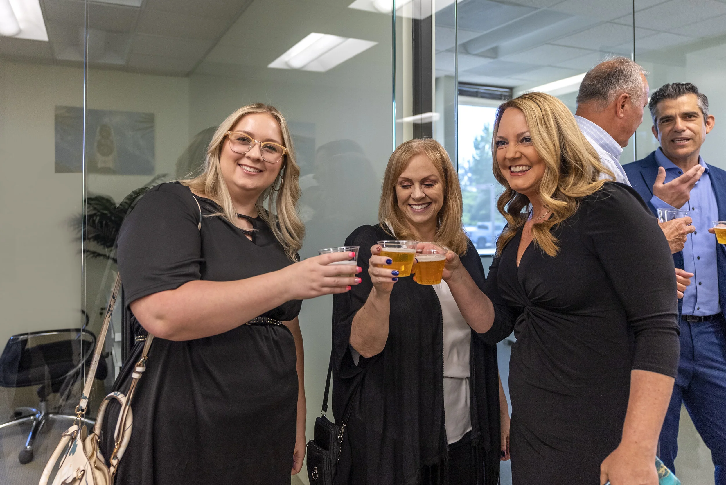 Group of five people at a social gathering, holding drinks, smiling, and raising glasses for a toast.