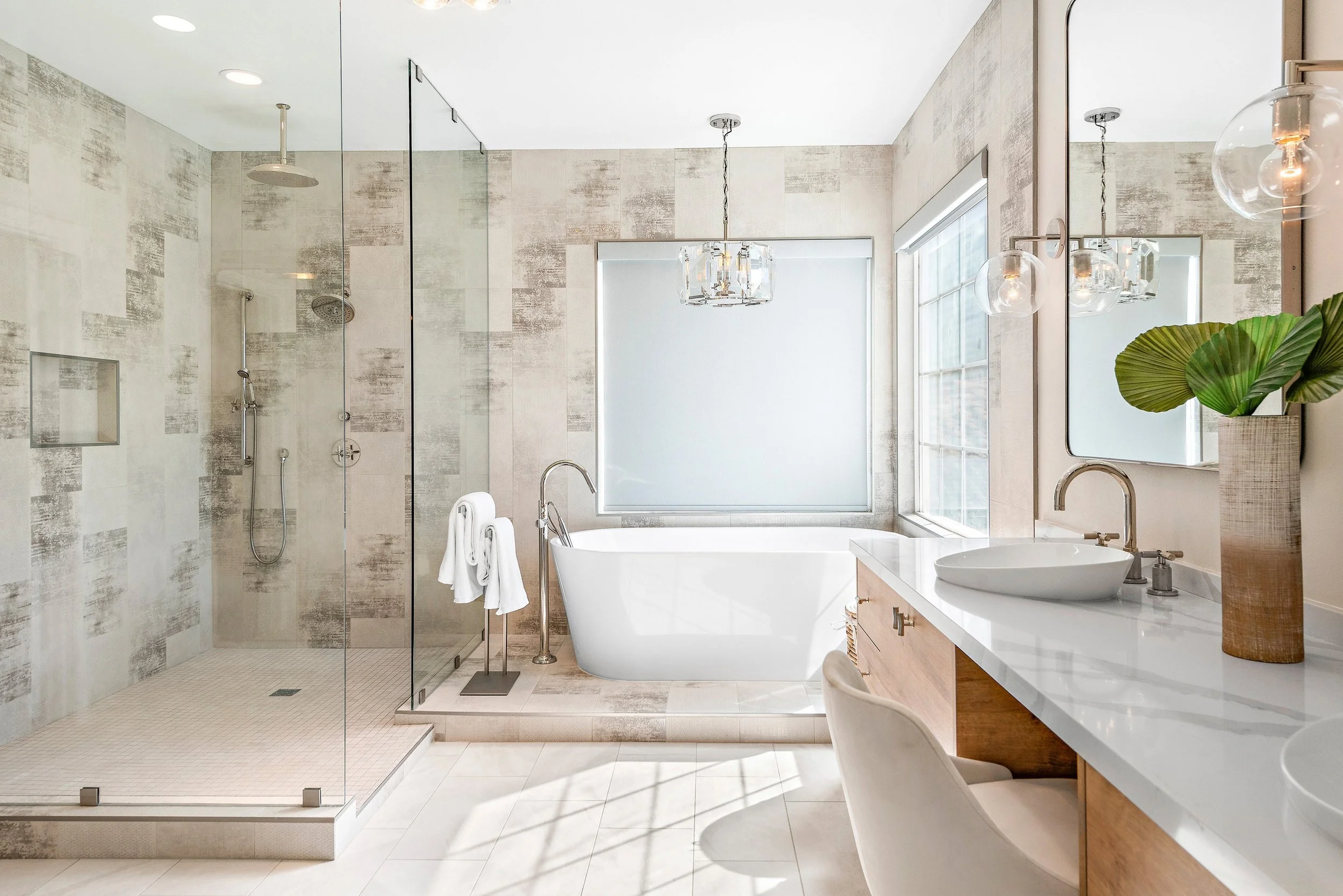 Modern bathroom with walk-in shower, freestanding bathtub, vanity with vessel sink, large mirror, and decorative plant.