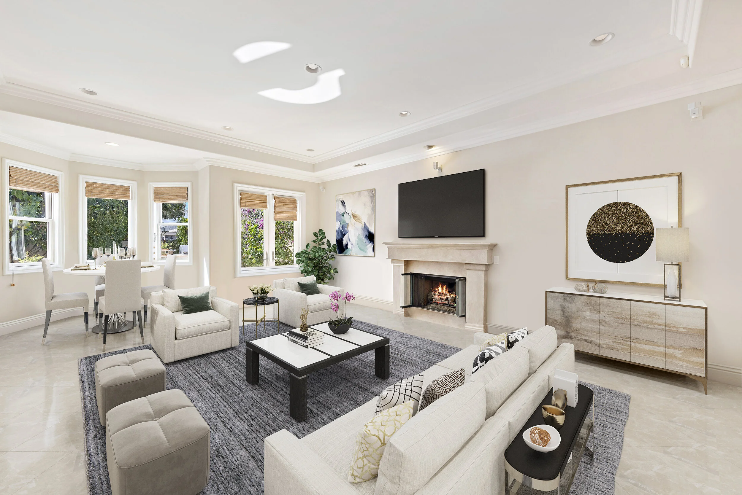 Bright living room with beige furniture, black and white coffee table, fireplace, large wall-mounted TV, abstract wall art, sideboard with artwork and lamp, and windows with natural light.