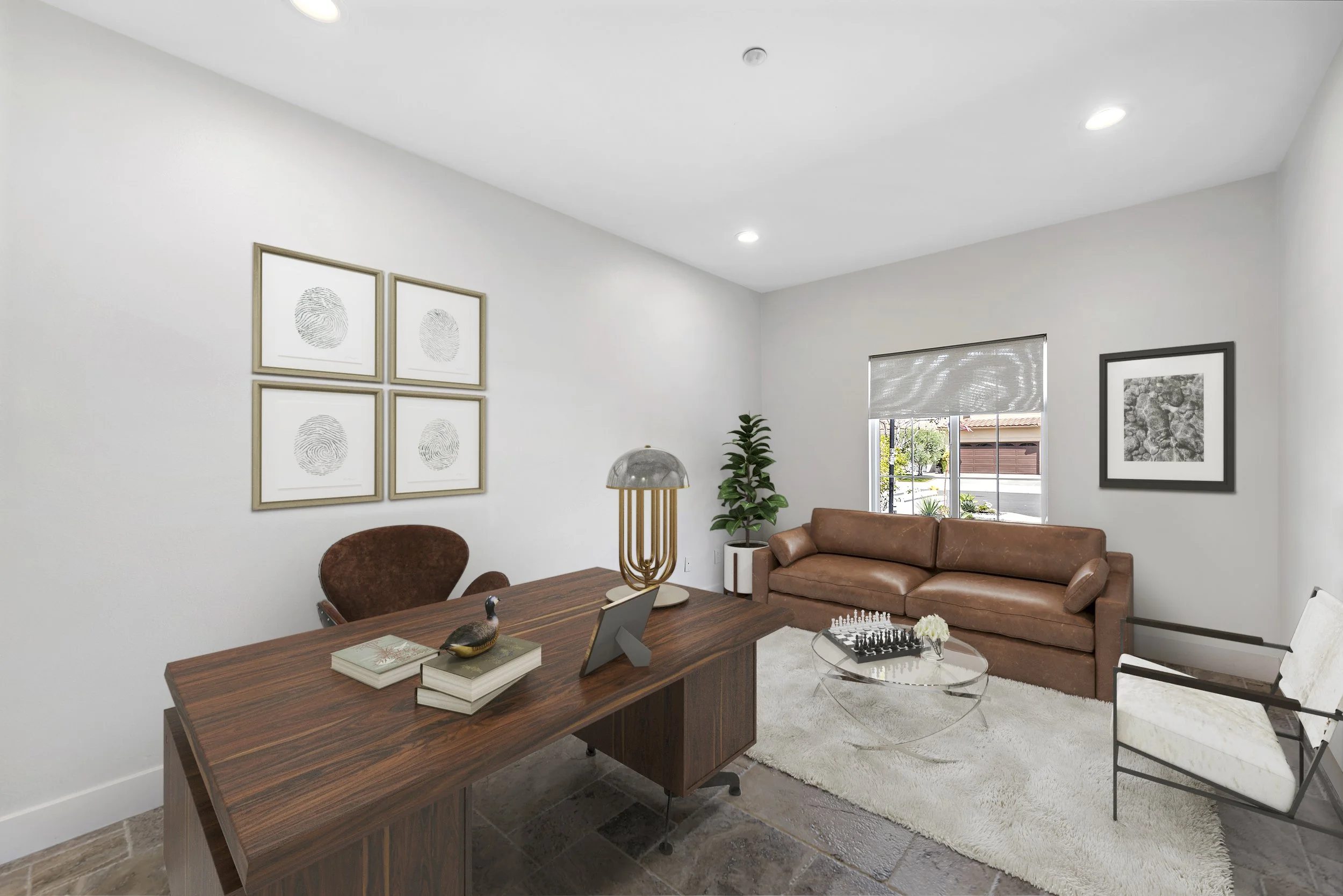 Modern office with a wooden desk, brown leather sofa, white armchair, glass coffee table with chess set, artwork on white walls, potted plant, and window with roller shade.