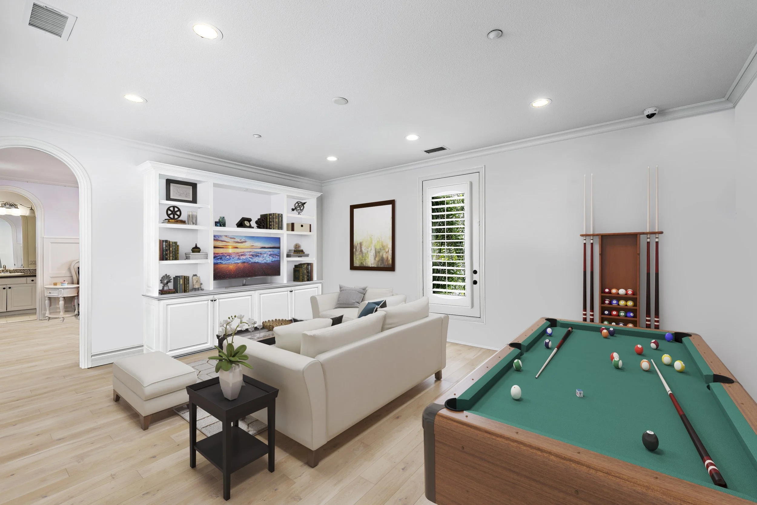 Living room with white sofa, TV, bookshelf, and a pool table with balls and cues.