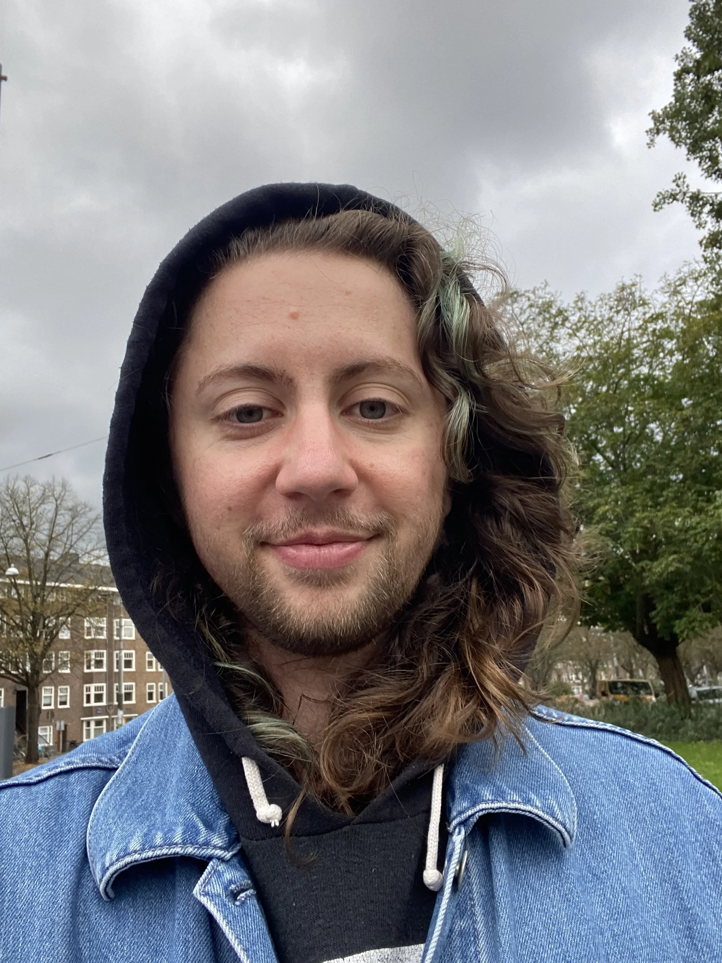 Photo of River from the shoulders up. River is a white non-binary person with long brown hair and a short beard.