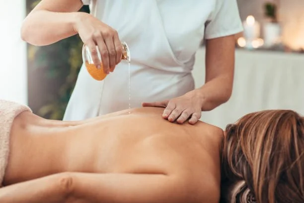 A person receiving a massage with oil from a therapist in a spa setting.