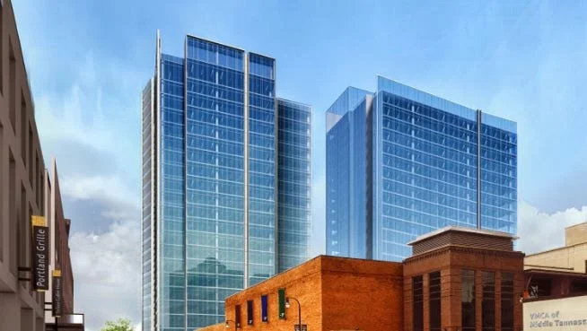 Modern glass skyscrapers behind a brick building on a city street.