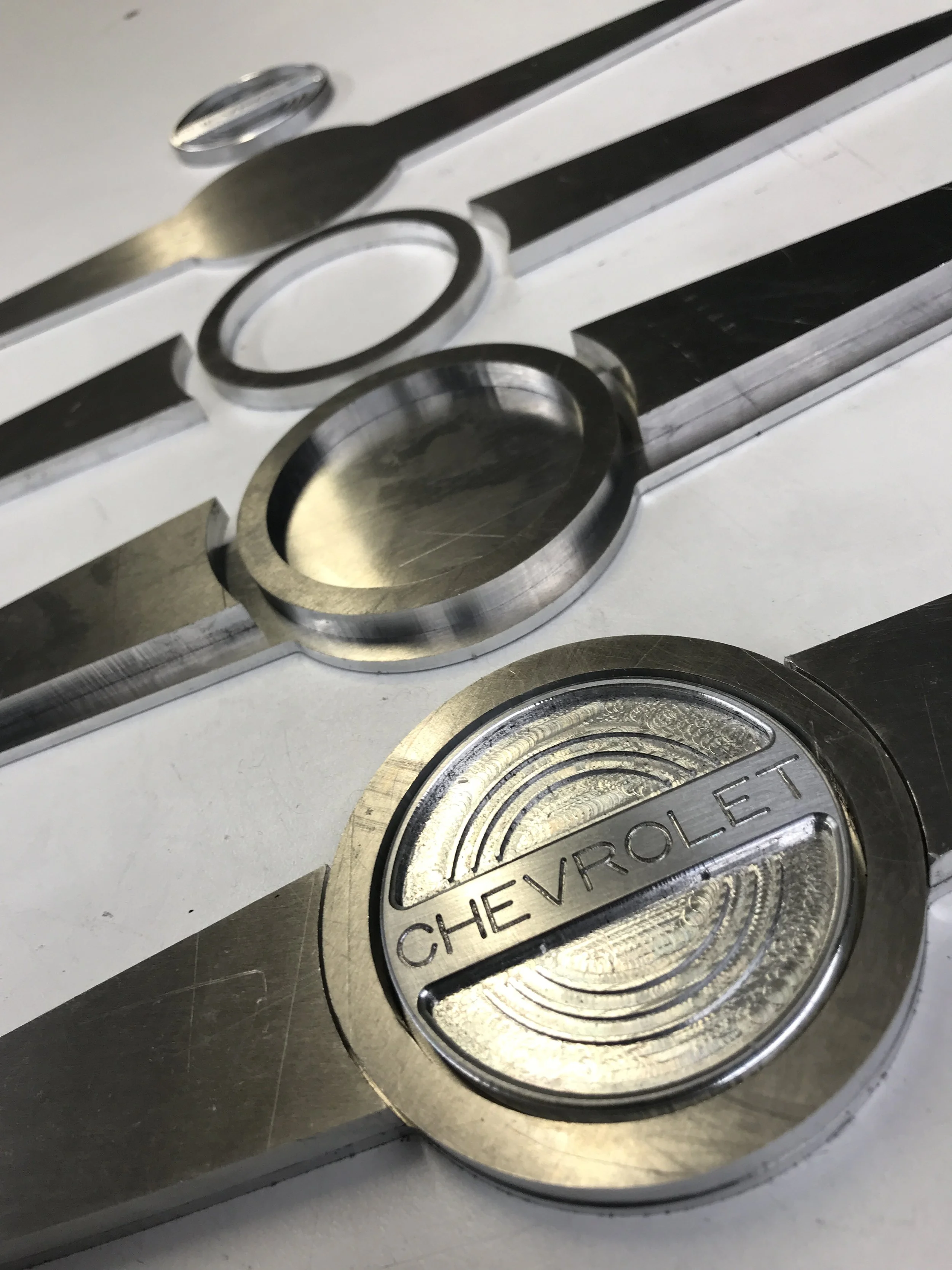 Close-up of a metallic emblem with the brand name "CHEVROLET" engraved on a circular icon, part of a car badge or logo.