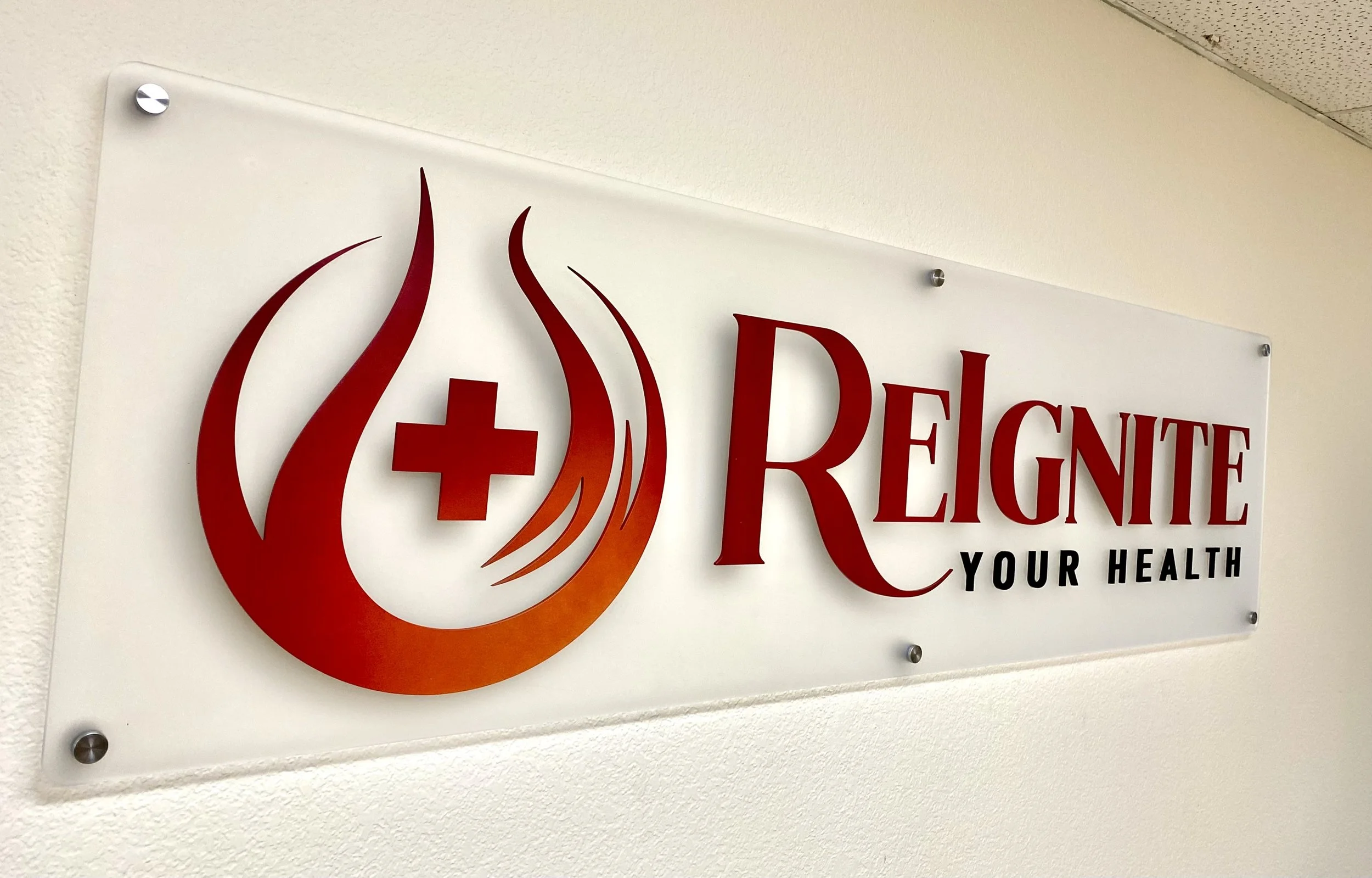 Sign for Reignite Your Health featuring a red flame, a medical cross, and the words "Reignite Your Health" in large red letters.