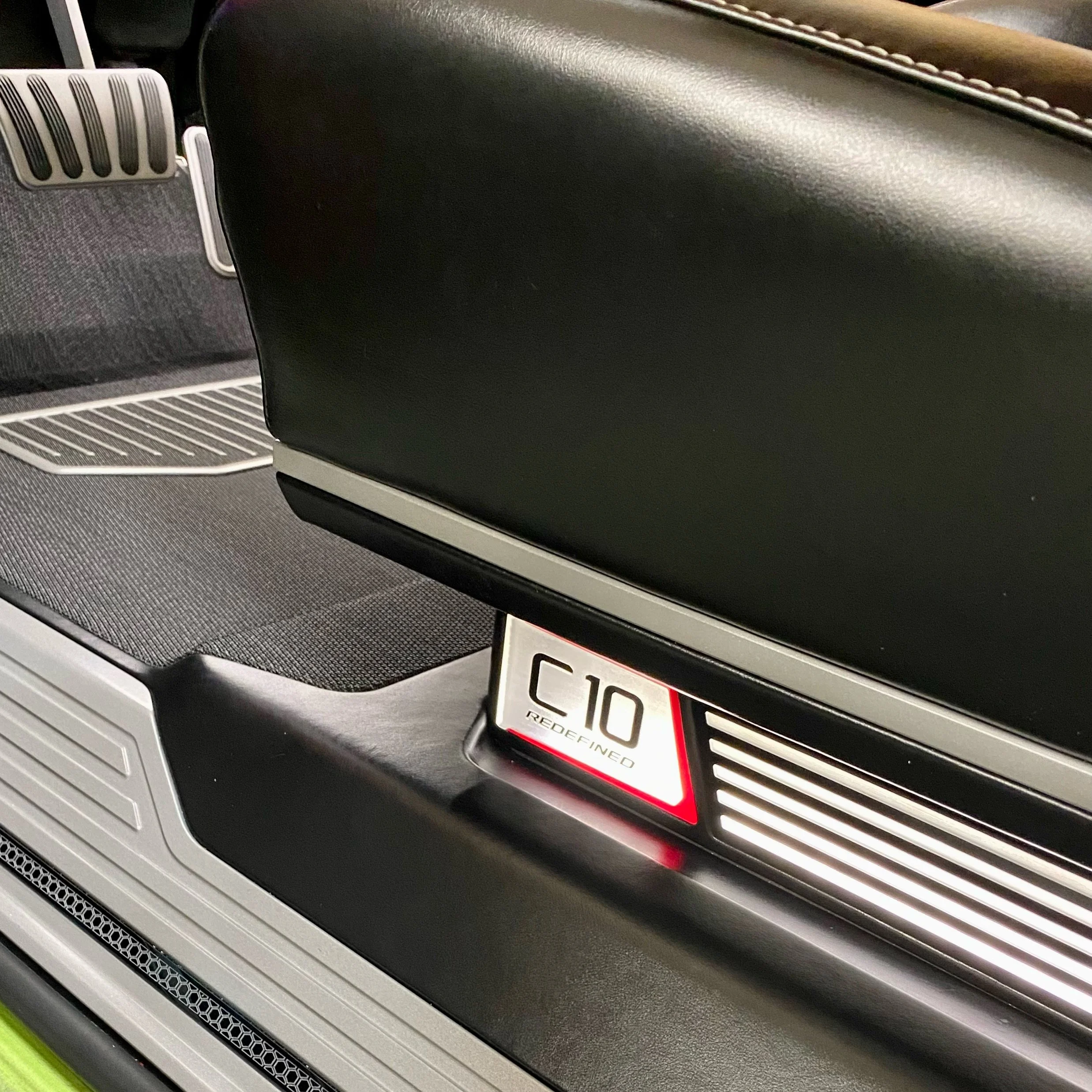 Close-up of a seat back with a badge reading 'C10 REDEFINED' on the floor underneath in a modern vehicle interior.