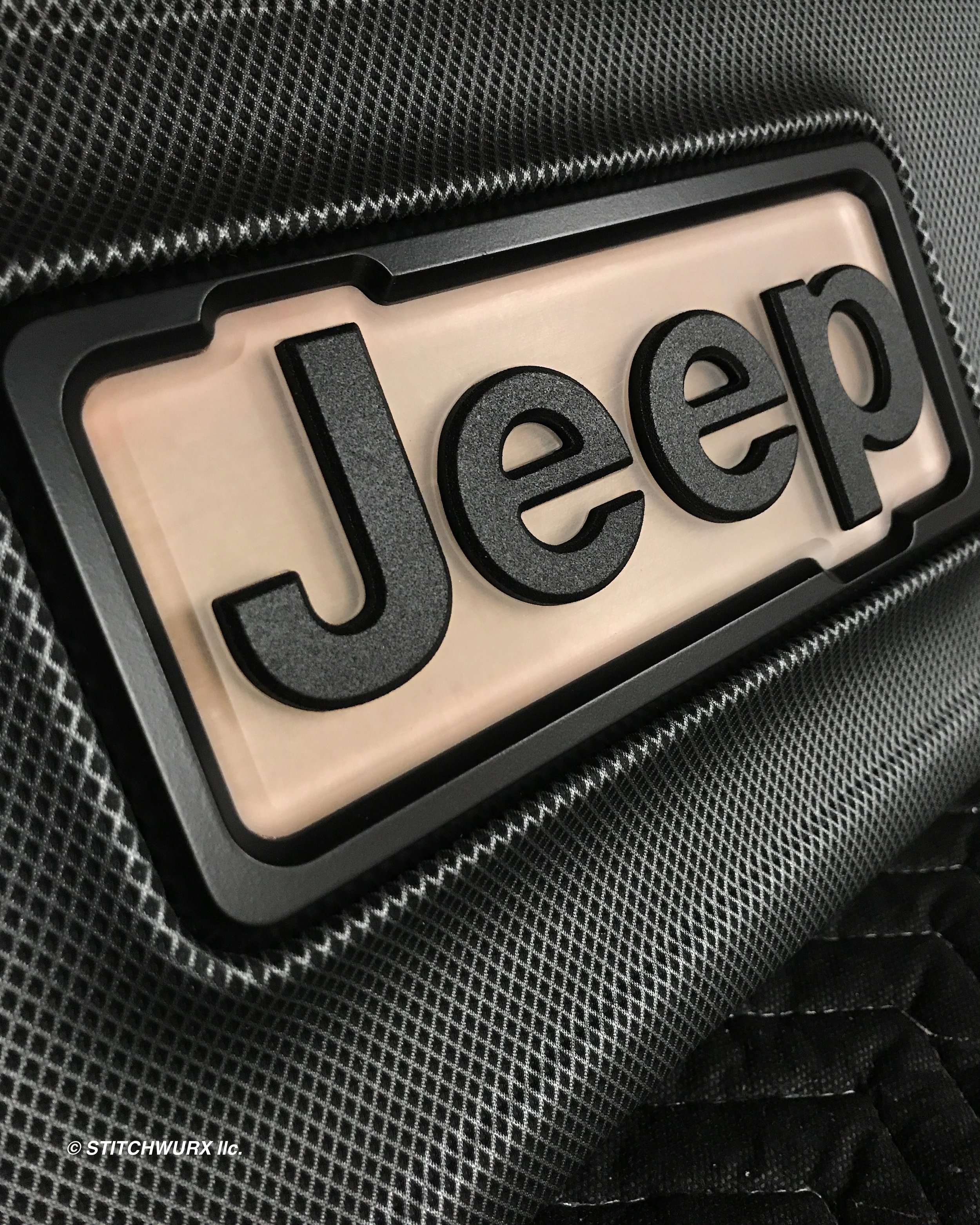 Close-up of a Jeep logo on a textured black backpack.