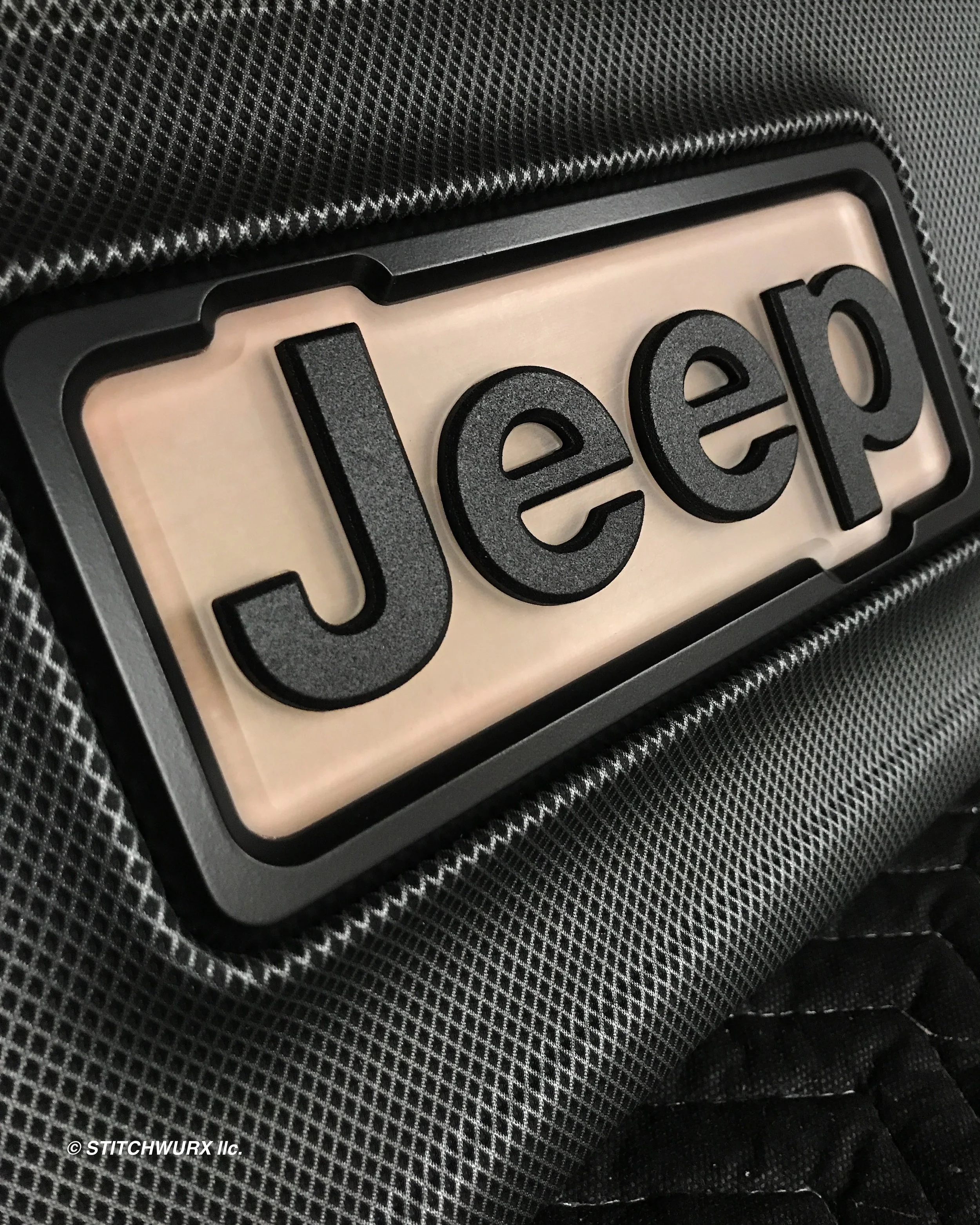 Close-up of a Jeep logo on the back of a vehicle or accessory, with black letters on a white background.