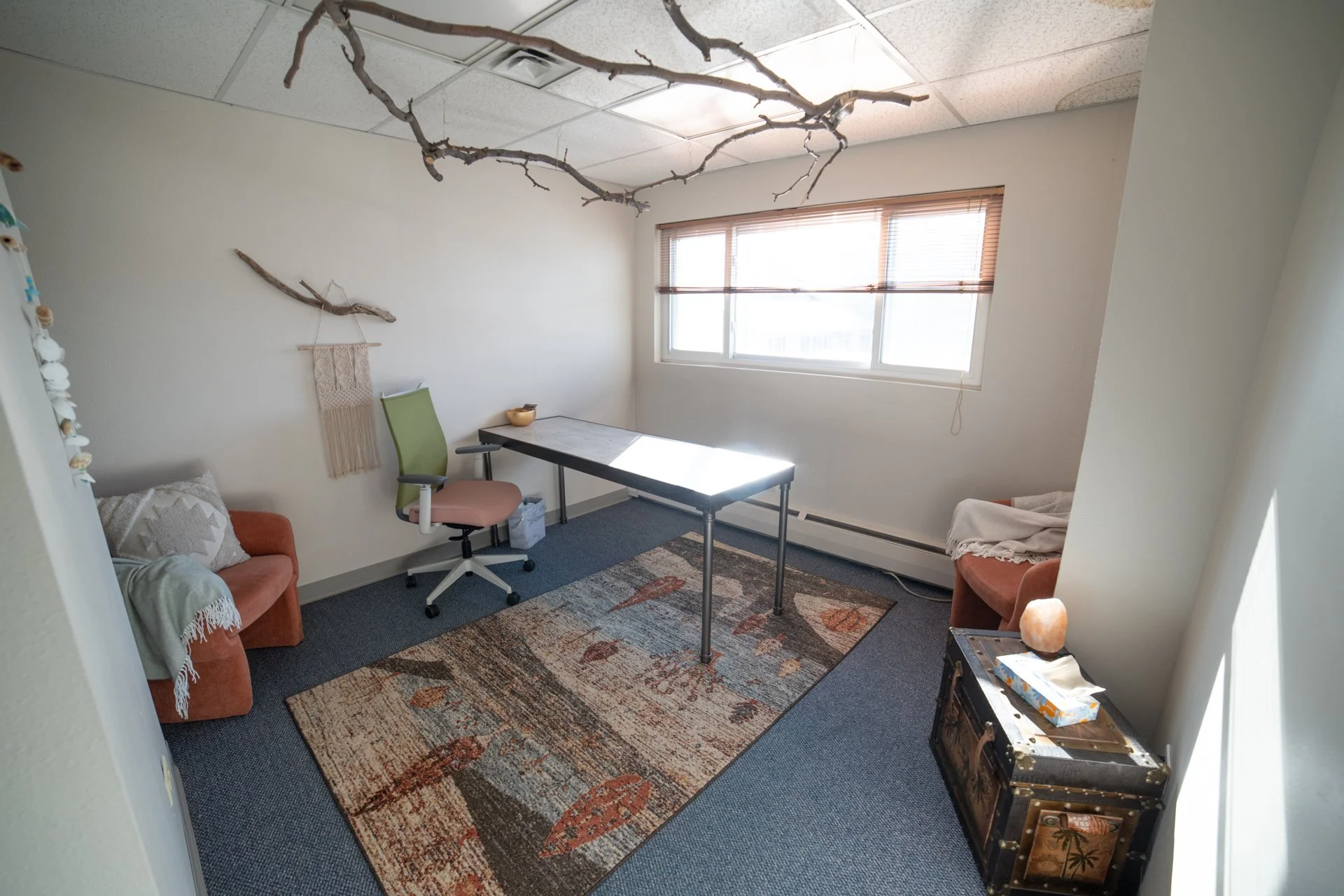 Office space with desk, cozy chairs, and bright, sunny window