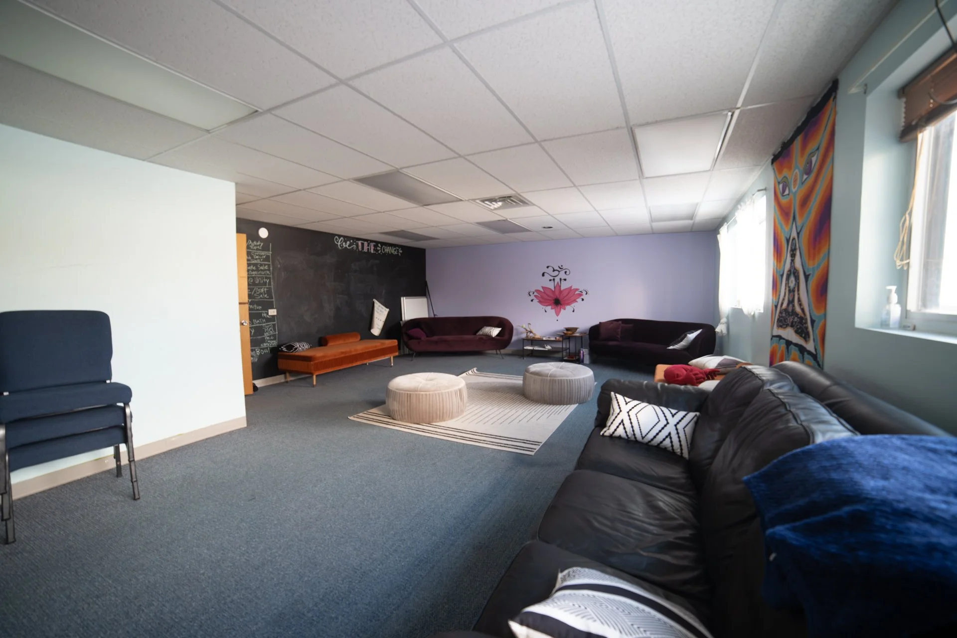 Long room with open floor space and multiple couches in warm jewel tones