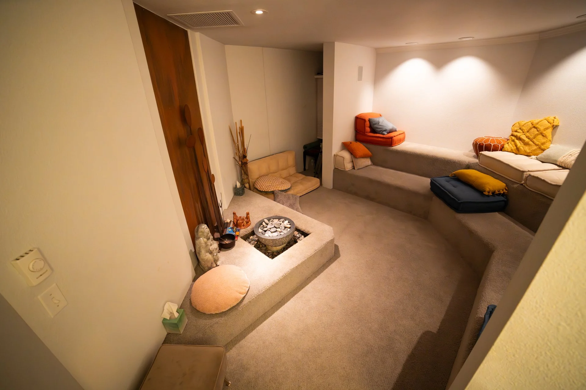 Room with cream walls, a water feature, and seating with multicolor throw pillows