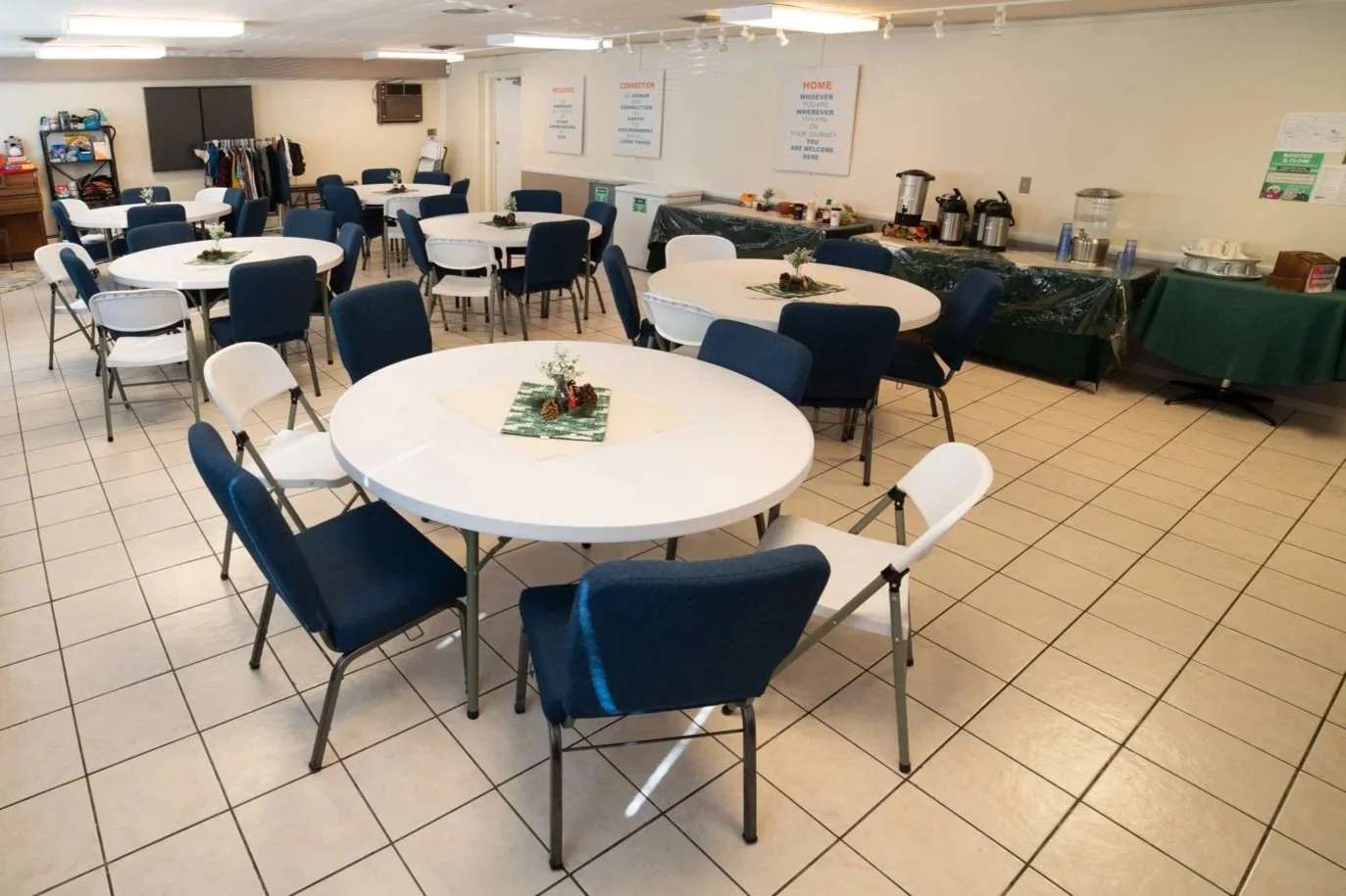 Large tiled room with round tables and blue chairs