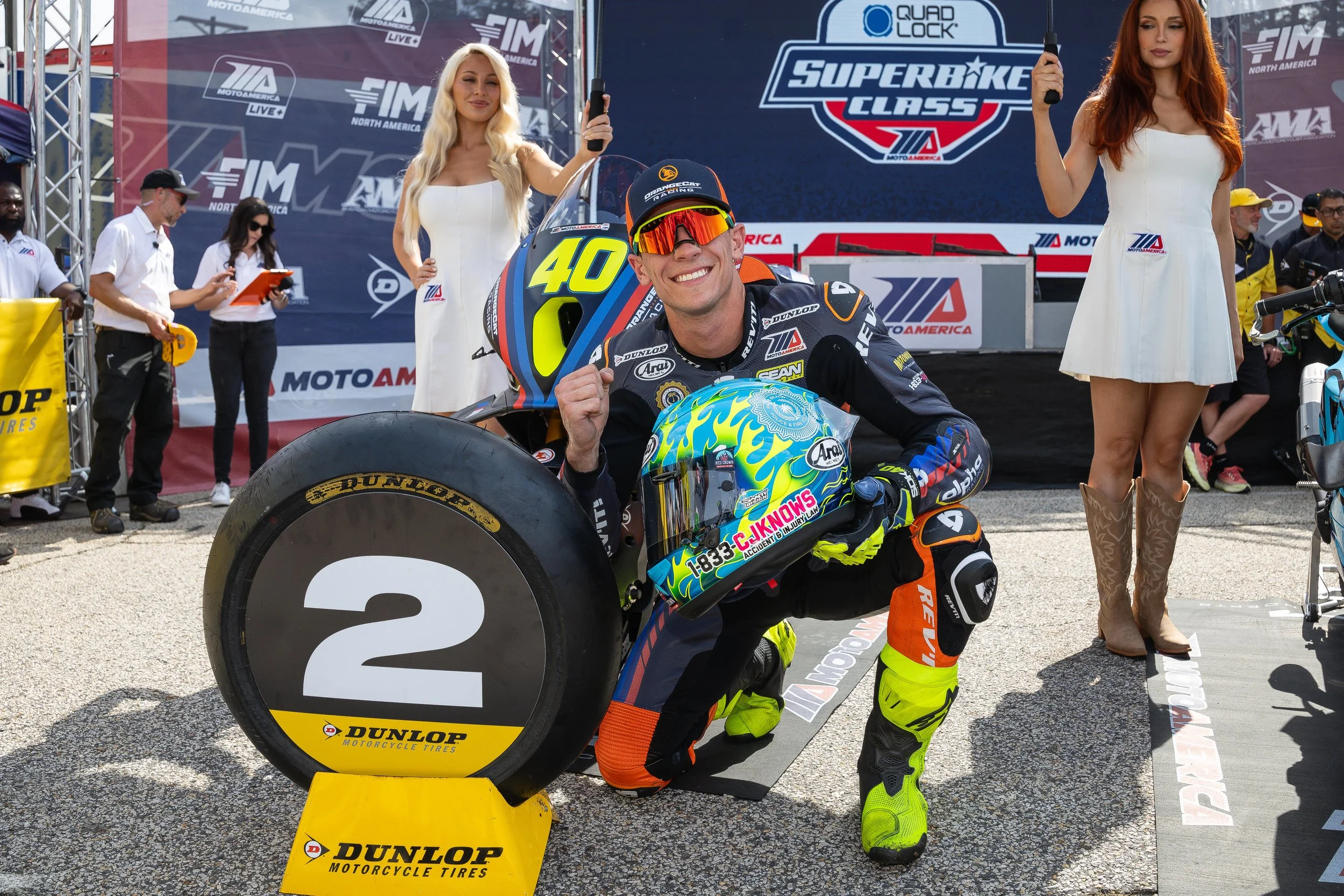 Sean Dylan Kelly in front of his BMW M 1000 RR on the podium, celebrating a second-place finish in his first Superbike race with OrangeCat Racing.