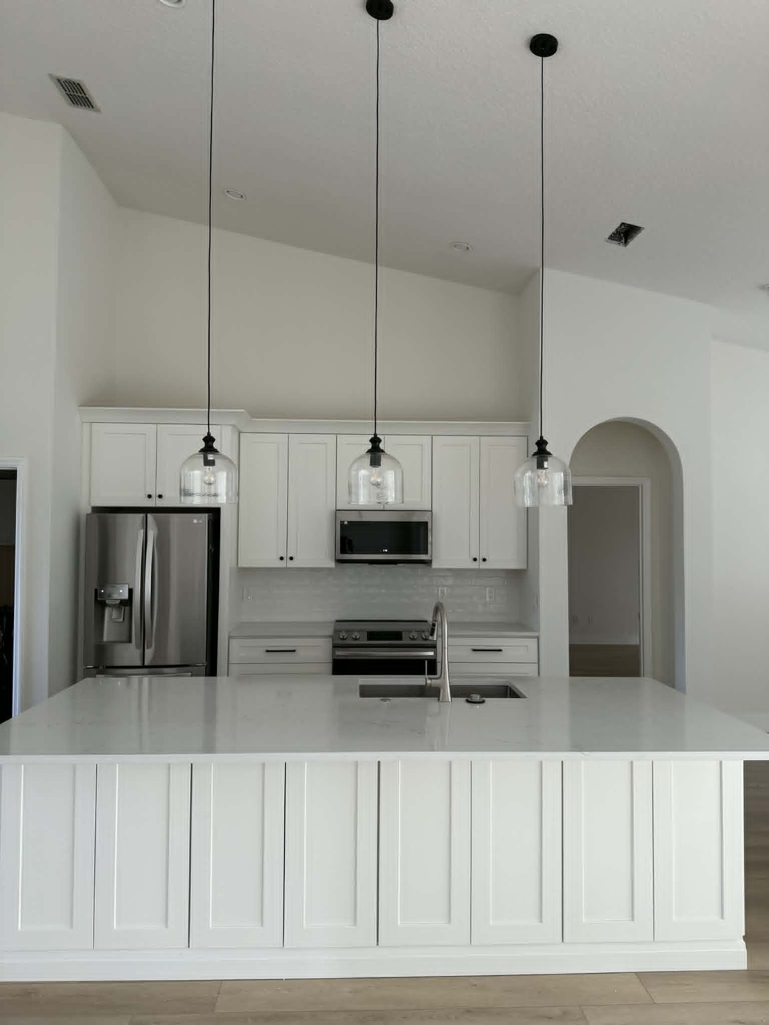 Modern Orlando kitchen remodel featuring an open-concept layout, custom white shaker cabinets, quartz waterfall island, pendant lighting, subway tile backsplash, and stainless steel appliances.