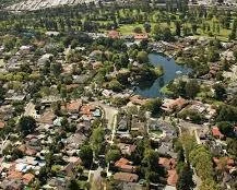 Aerial view of a suburban neighborhood with houses, trees, and a pond